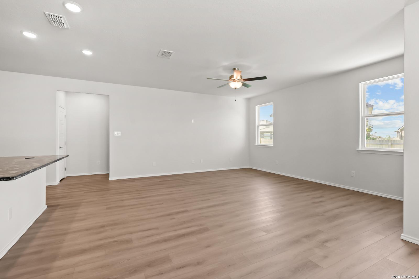 Open-concept living area with wood-look flooring and ceiling fan in Davidson Homes The Daphne I, Bricewood, San Antonio Texas