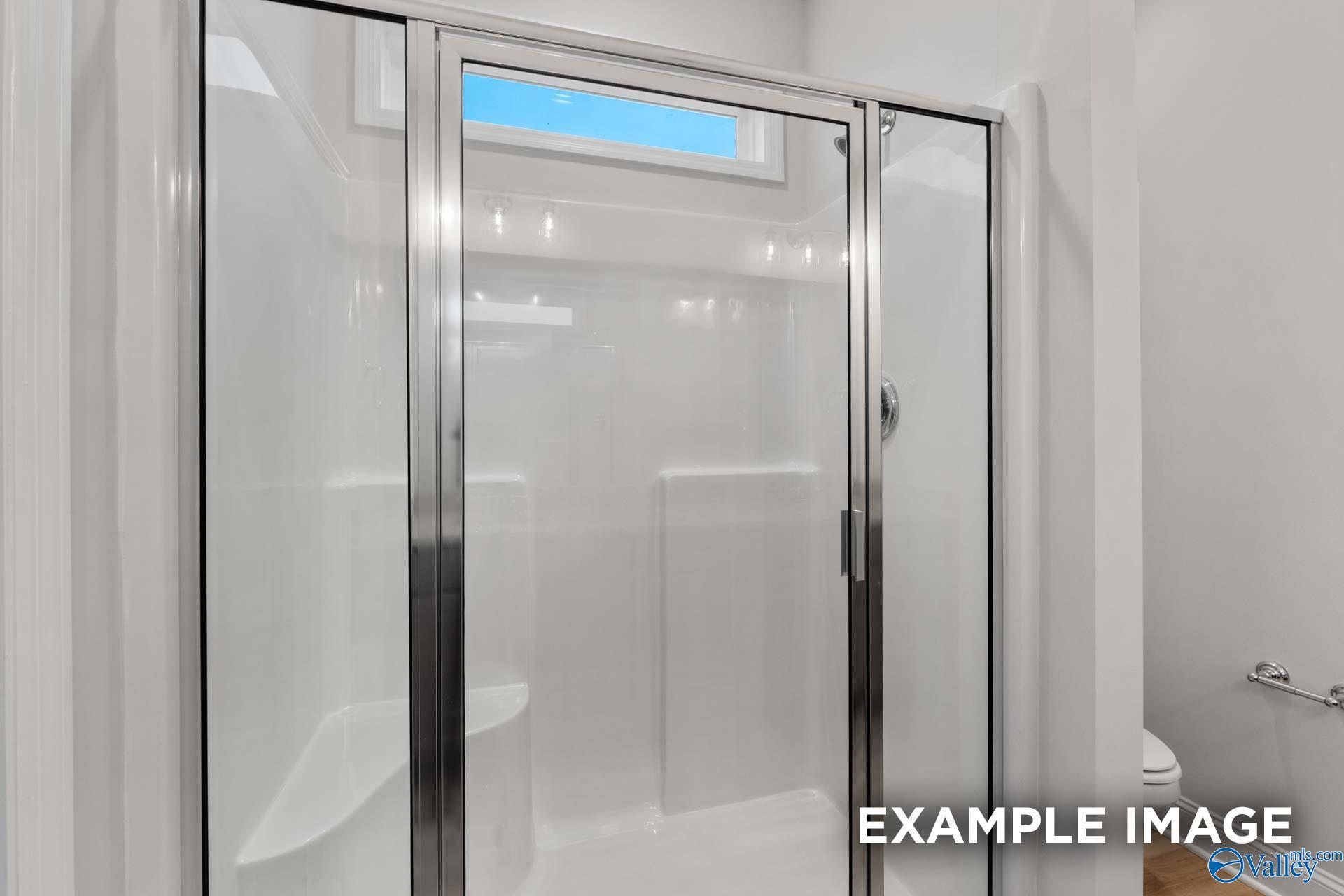 Modern frameless glass shower with white tile surround and window in Davidson Homes Cumberland B bathroom, Decatur AL
