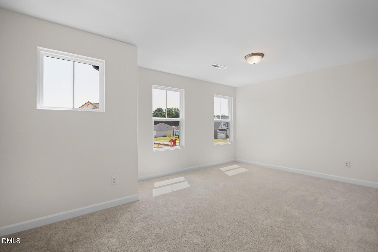 Bright carpeted bedroom with windows overlooking Woodland Crossing in Davidson Homes' The Willow B, Zebulon, North Carolina