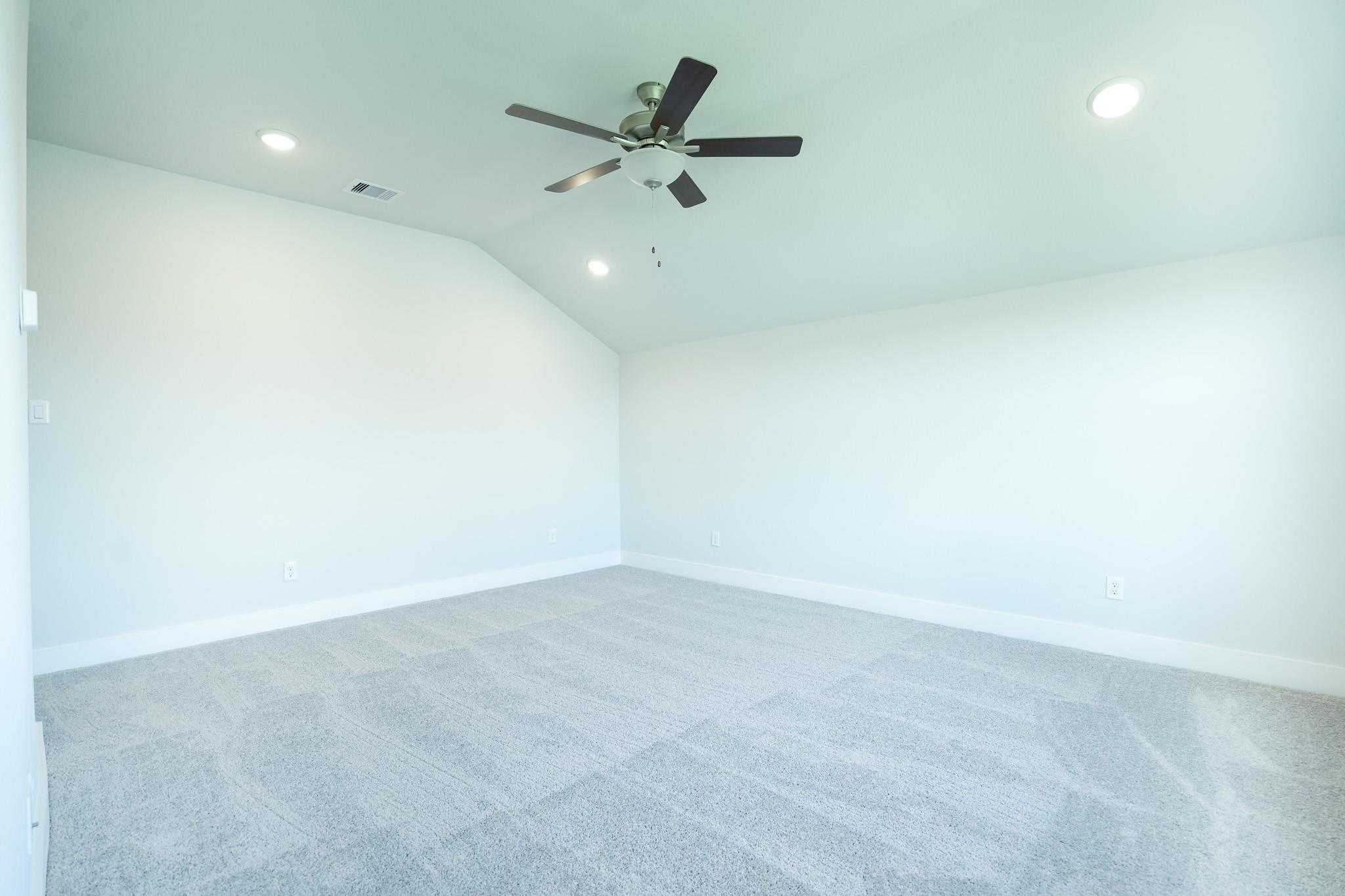 Spacious empty bedroom with vaulted ceiling, ceiling fan and beige carpet in Davidson Homes The Edward C, Lago Mar