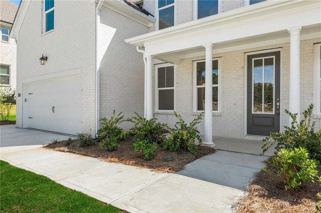 White brick 2-story Davidson Homes Danbury E with columned porch, dark door, 3-car garage, and landscaped entry in Buford, GA