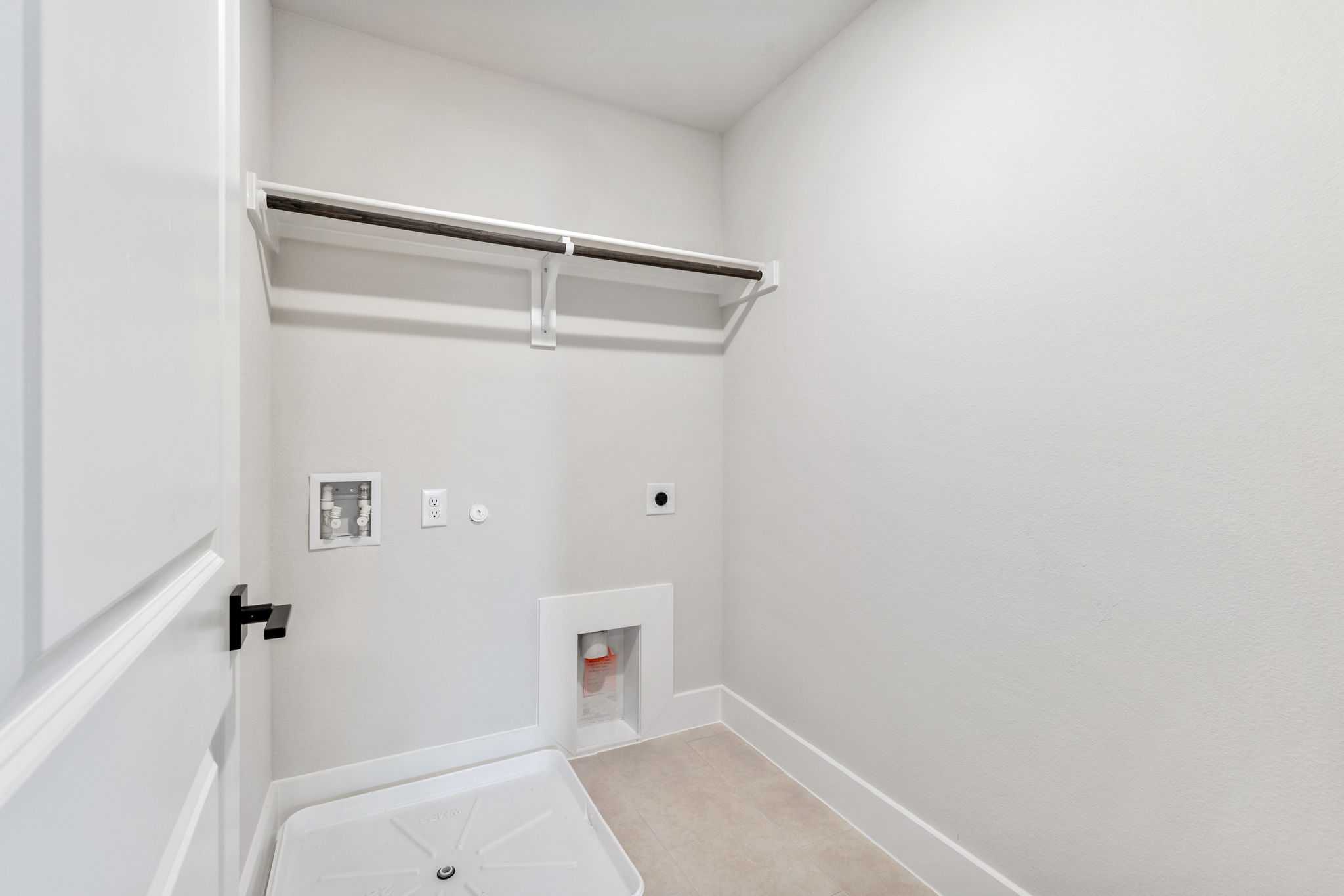 Spacious laundry room with built-in shelves, hanging rod, and washer/dryer hookups in Davidson Homes The Durham E, Wylie, Texas
