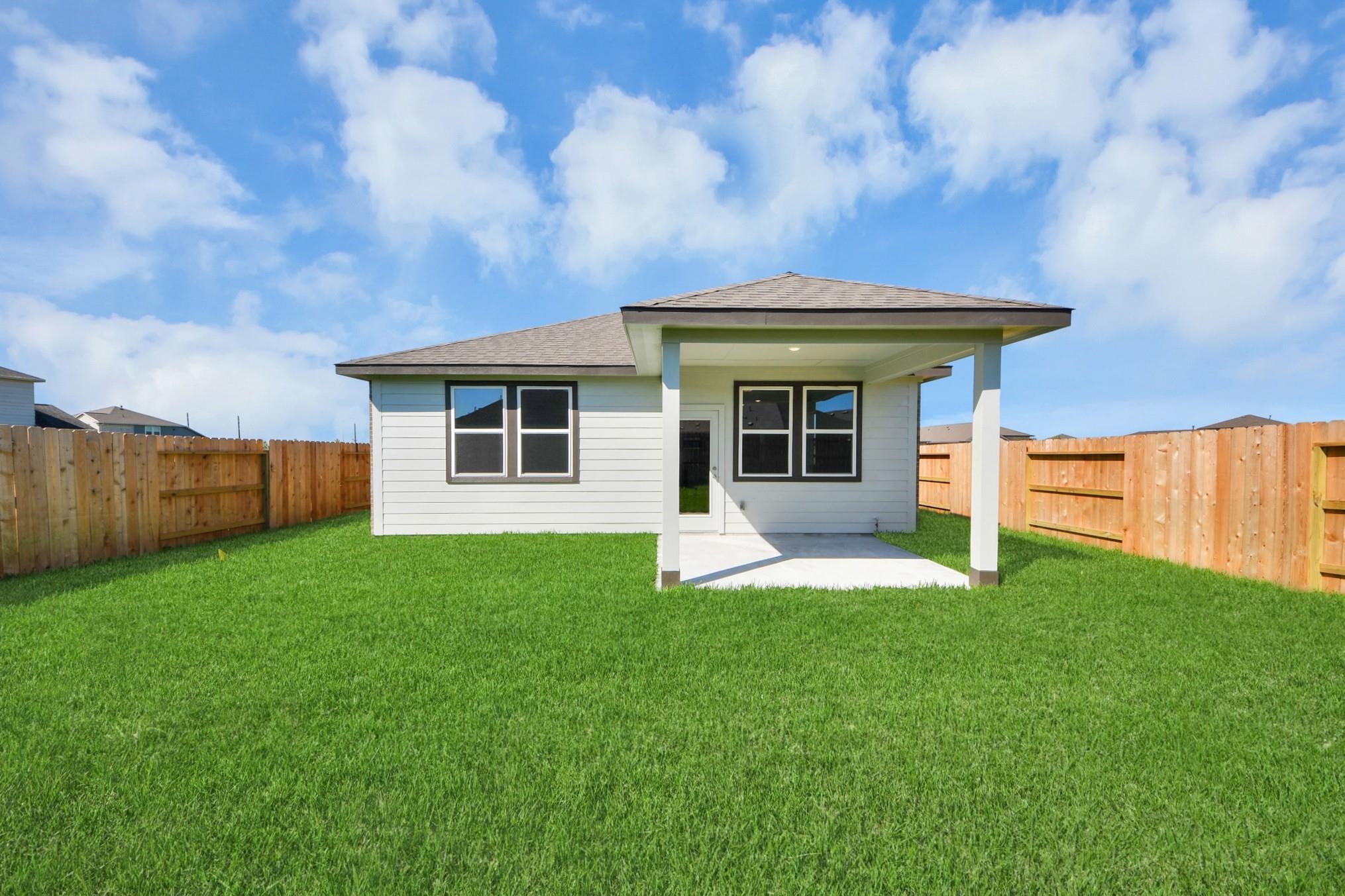 Covered back patio and spacious fenced backyard of The Colorado G floor plan at Emberly in Beasley, Texas.
