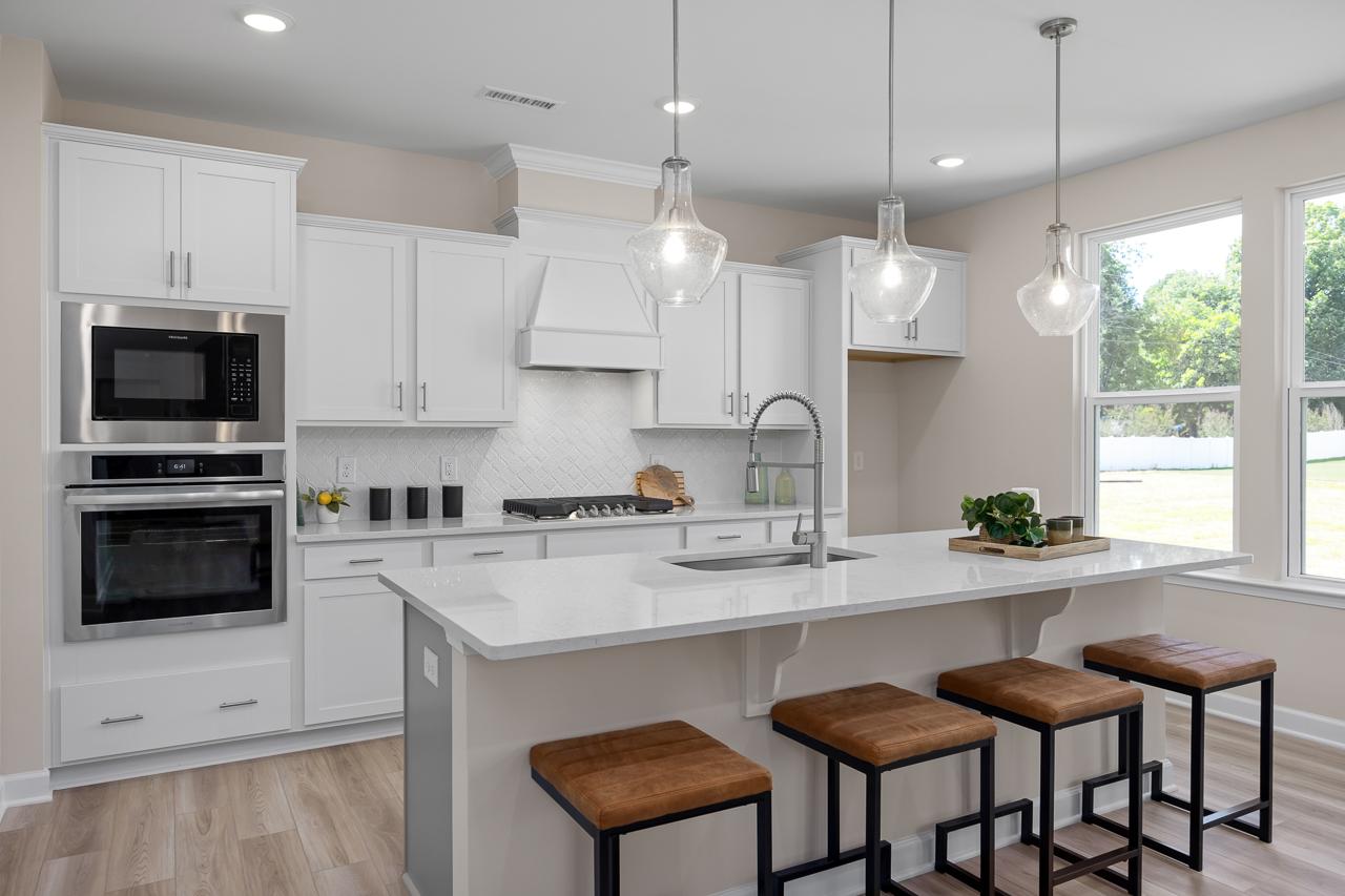 Modern kitchen in The Chestnut A featuring white cabinets, quartz countertops, a large island, and stainless steel appliances.