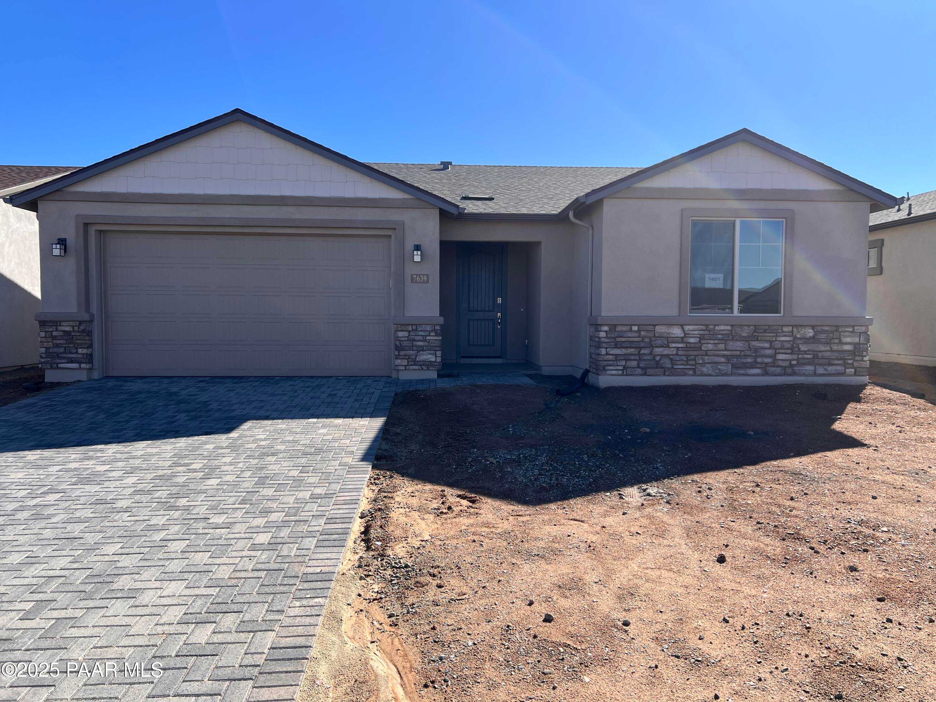 Modern 1-story 3-car garage home exterior with stone accents and paver driveway in North Ridge at Pronghorn Ranch, Prescott Valley, Arizona - Davidson Homes The Harmony A