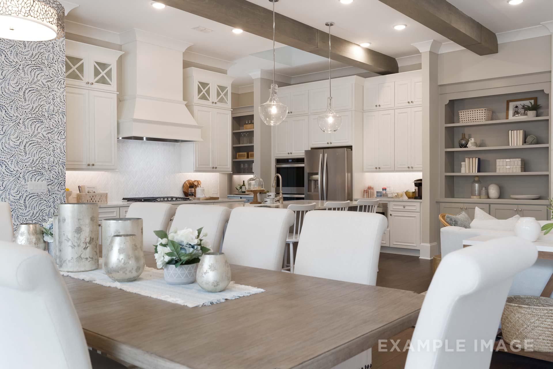Spacious open-concept kitchen dining in The Seaside C with white cabinets, large island, stainless appliances, pendant lights