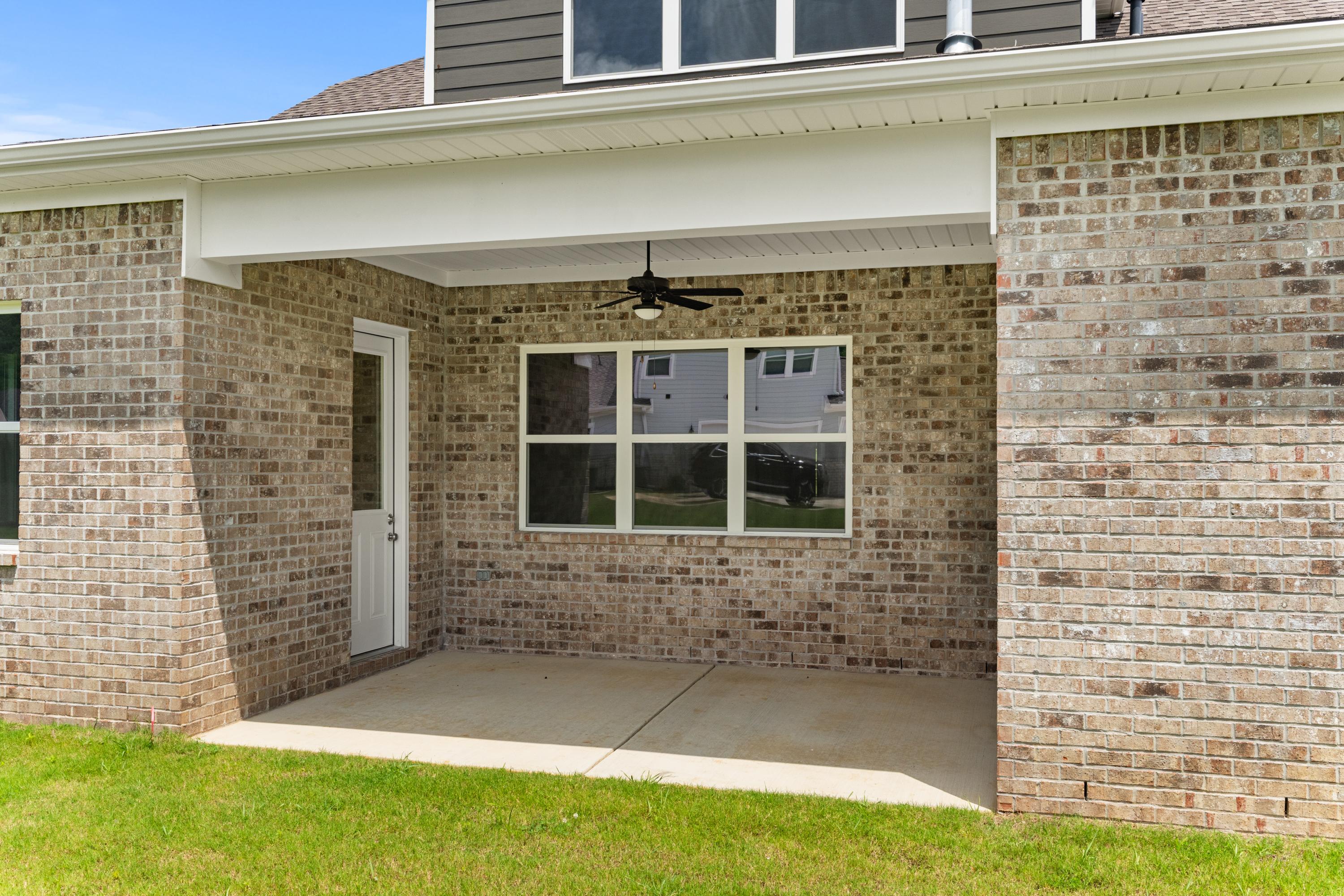 Rear elevation of The Oxford A showcasing brick exterior, covered porch with ceiling fan, large windows, and concrete patio