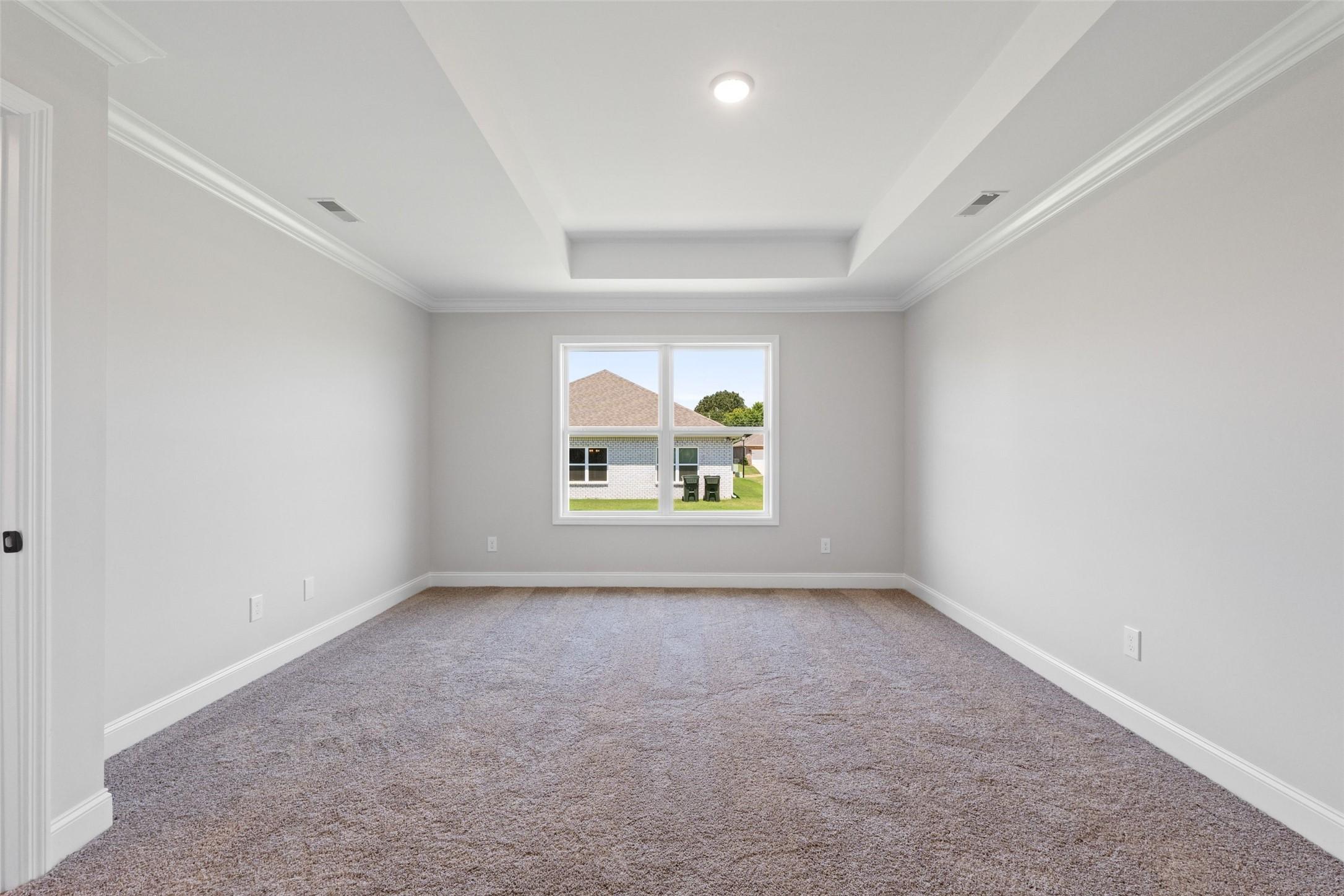 Spacious bedroom with tray ceiling and plush carpet in The Holly C floor plan by Davidson Homes in Anna, Texas.
