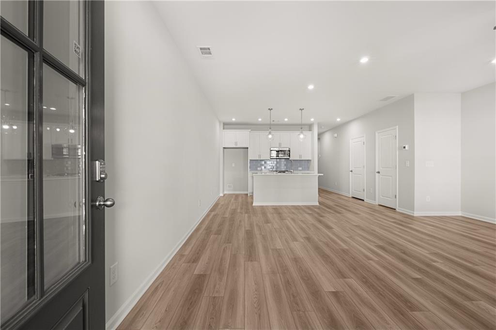 Open-concept floor plan in The Monroe B at Stegall Village, featuring modern white kitchen and wood-style flooring.