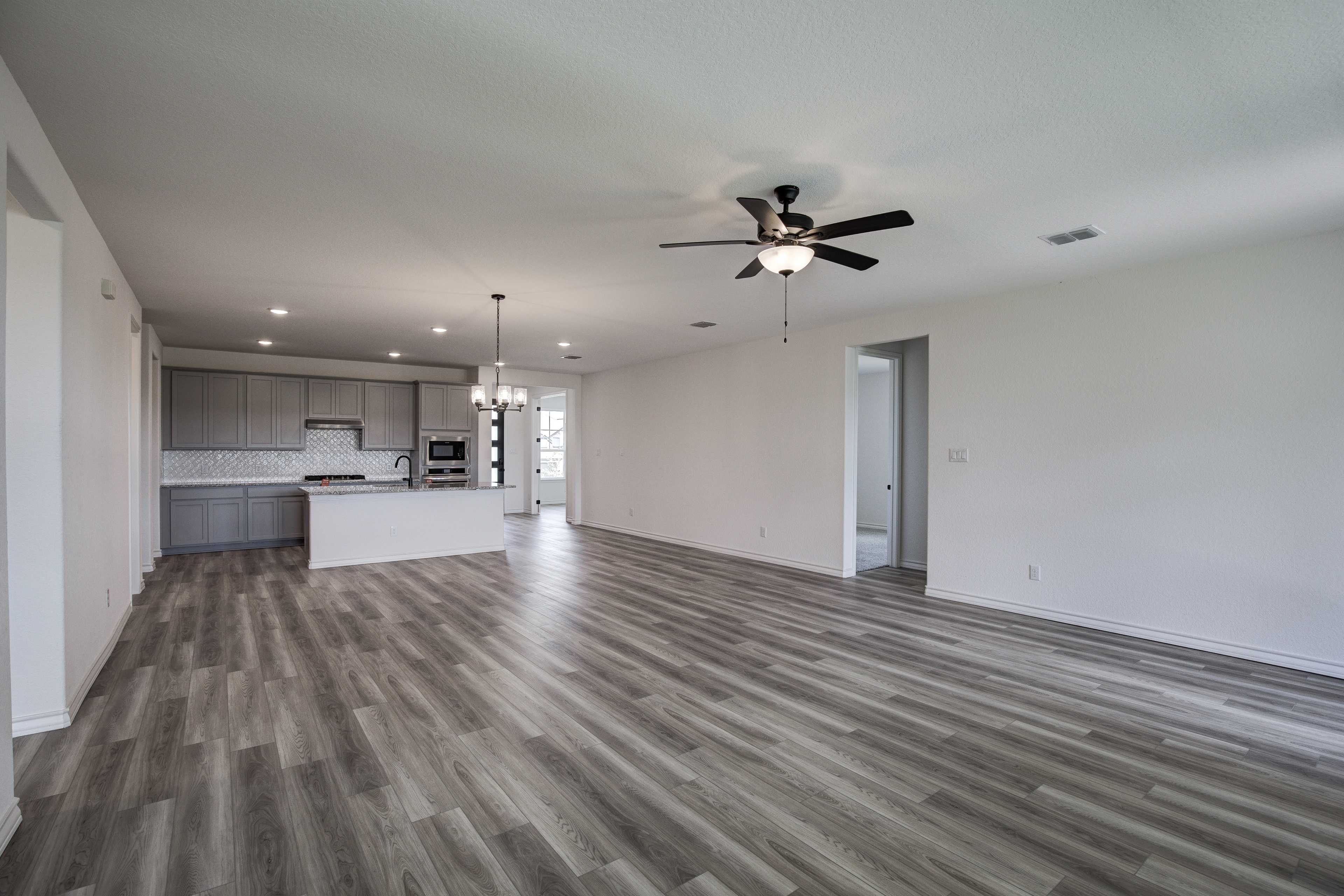 Spacious open-concept kitchen in The Lanier home by Davidson Homes, gray cabinets, large island, ceiling fan, luxury vinyl plank flooring