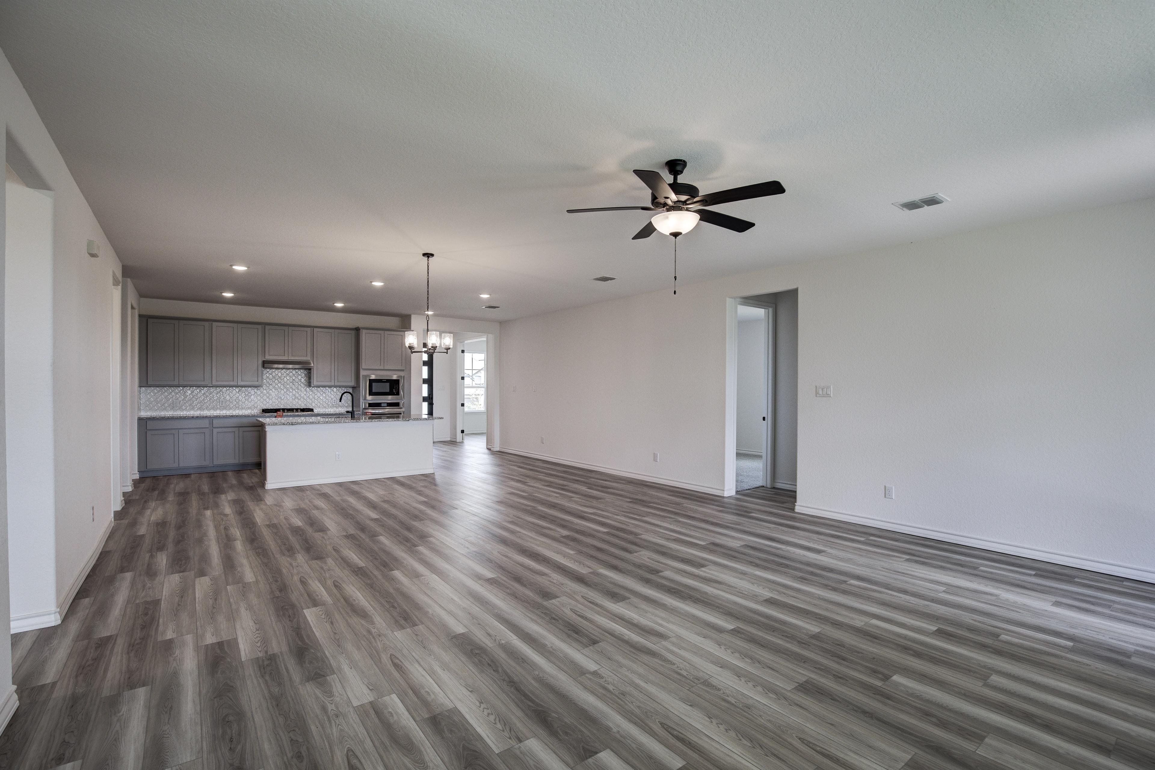 Spacious open-concept kitchen-living area in The Lanier floor plan by Davidson Homes, featuring gray cabinets, large island, ceiling fan