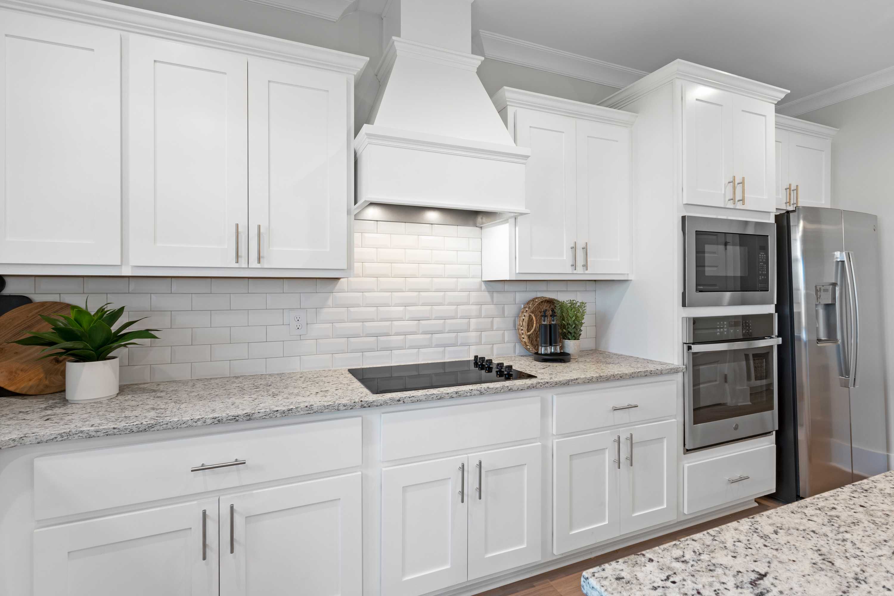 Modern kitchen in The Chelsea A with white shaker cabinets, granite counters, subway tile backsplash, and stainless steel appliances