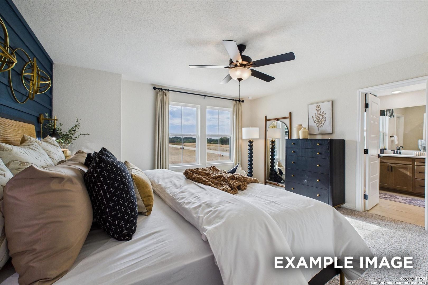 Cozy master bedroom with plush king bed, navy accent wall, ceiling fan, and en-suite bath in Davidson Homes The Florence C, San Antonio