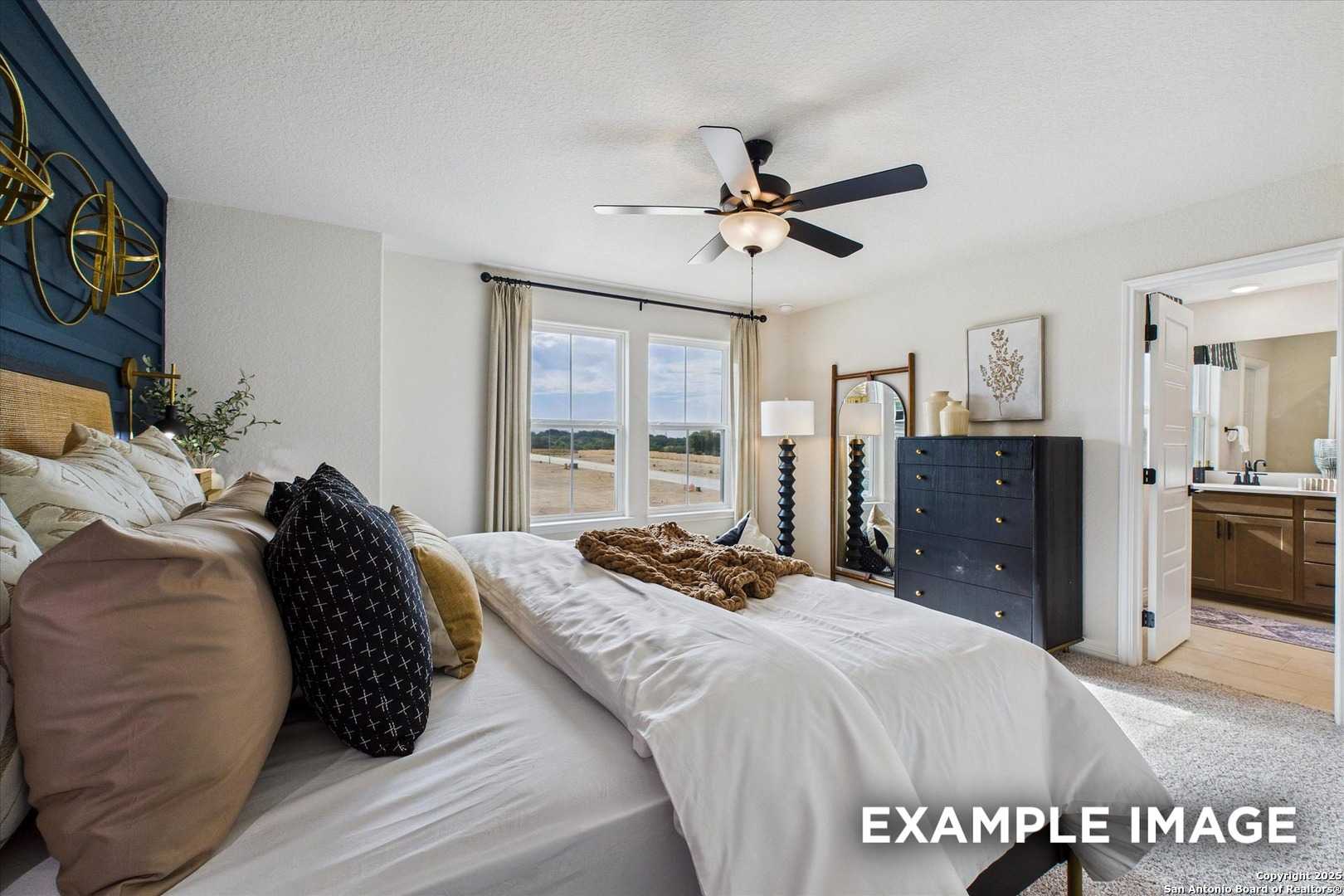 Cozy master bedroom with plush king bed, navy accent wall, ceiling fan, and en-suite bath in Davidson Homes The Florence C, San Antonio