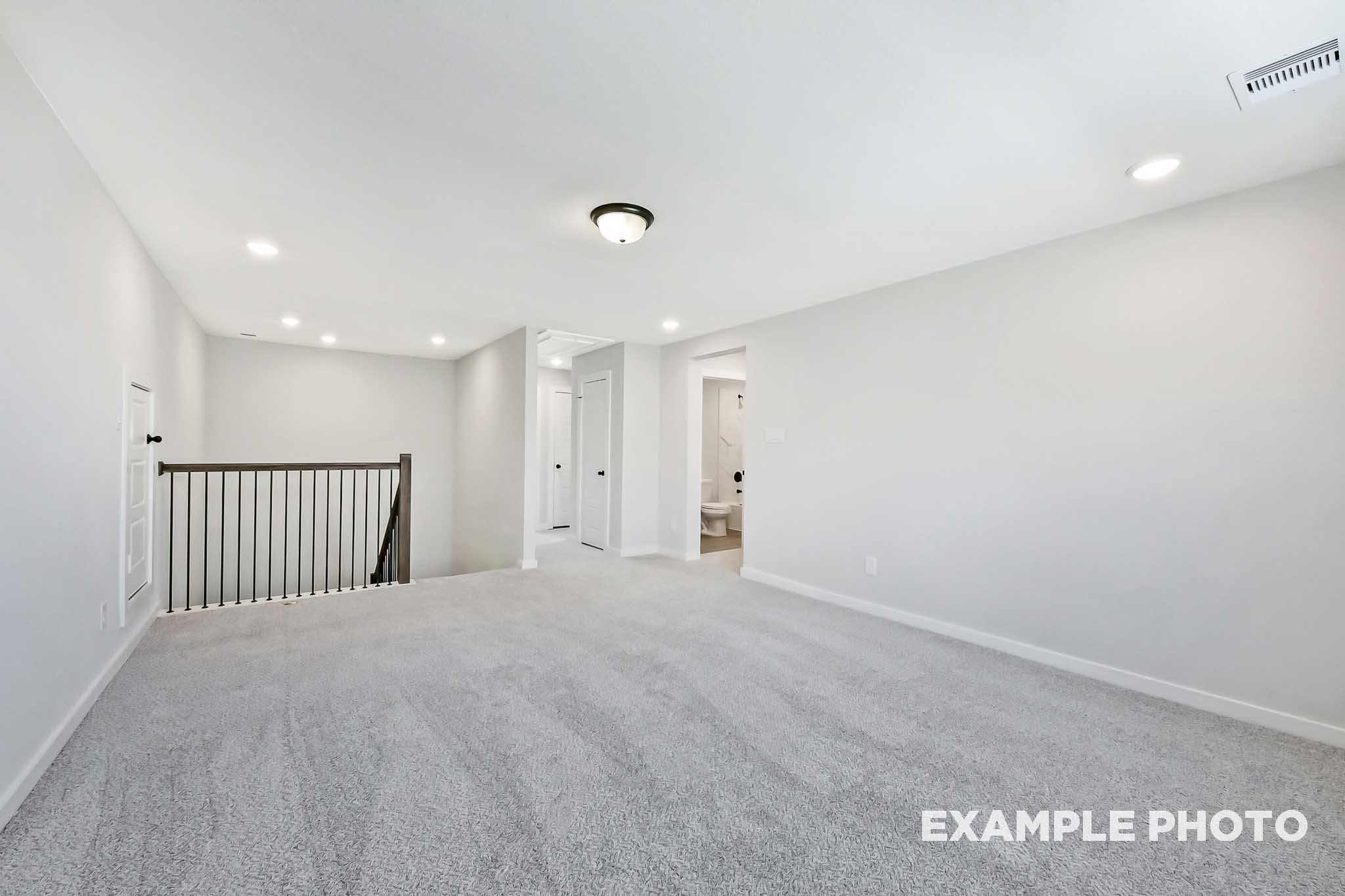 Spacious upstairs loft in The Sequoia 2-story home with gray carpet, white walls, bedroom doors, bathroom access, and overlook railing