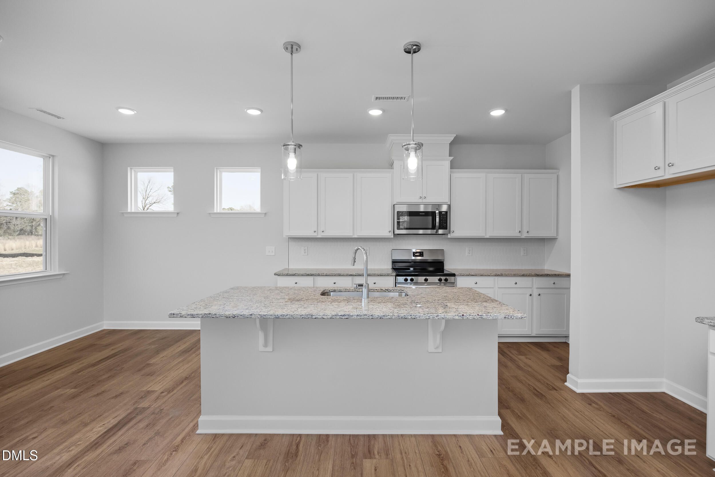 Modern kitchen with granite island, white cabinets, and stainless appliances in Gavin A floor plan at Gregory Village.