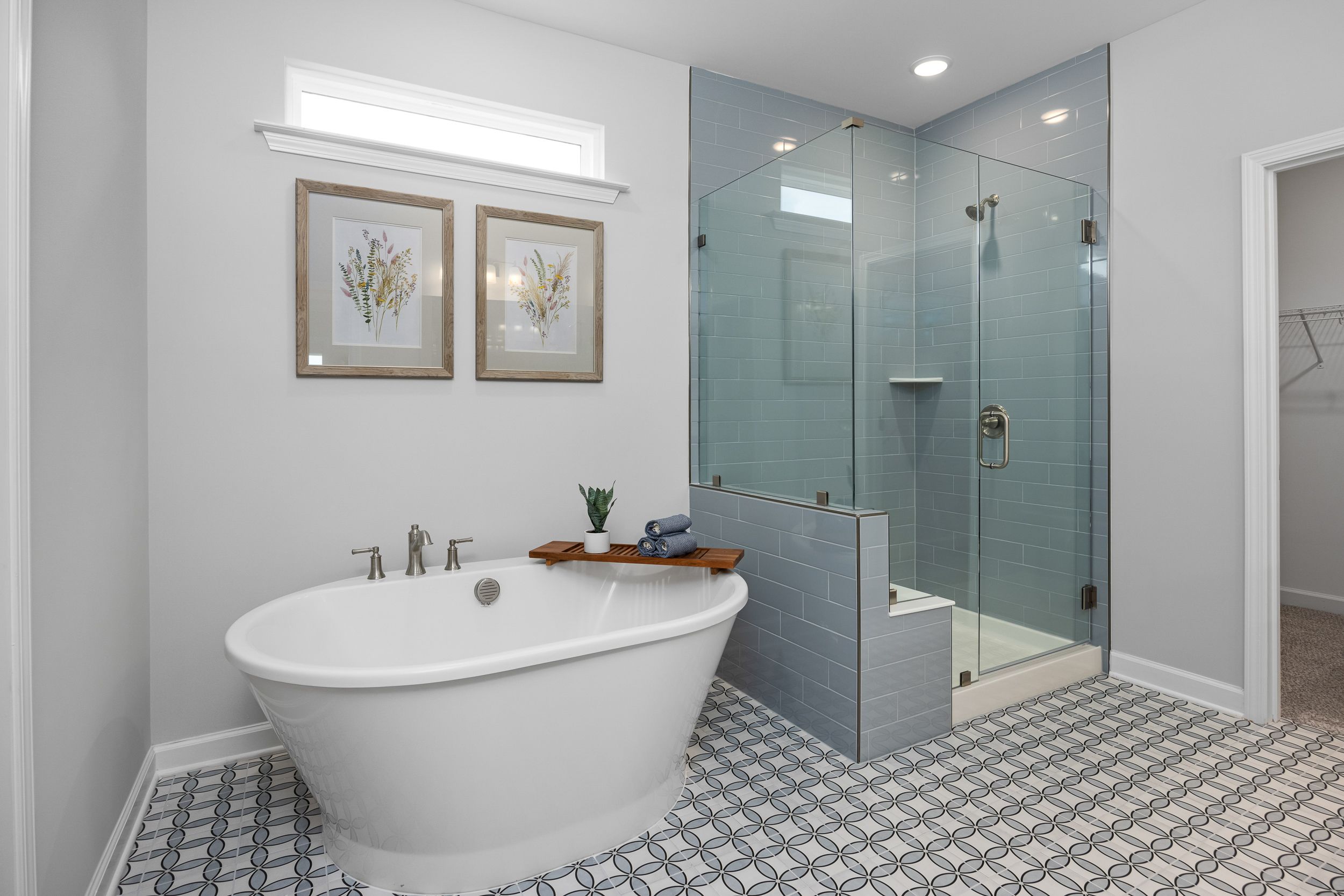 Elegant master bathroom in Addison West, Holly Springs NC with freestanding tub, glass shower, and subway tile accents