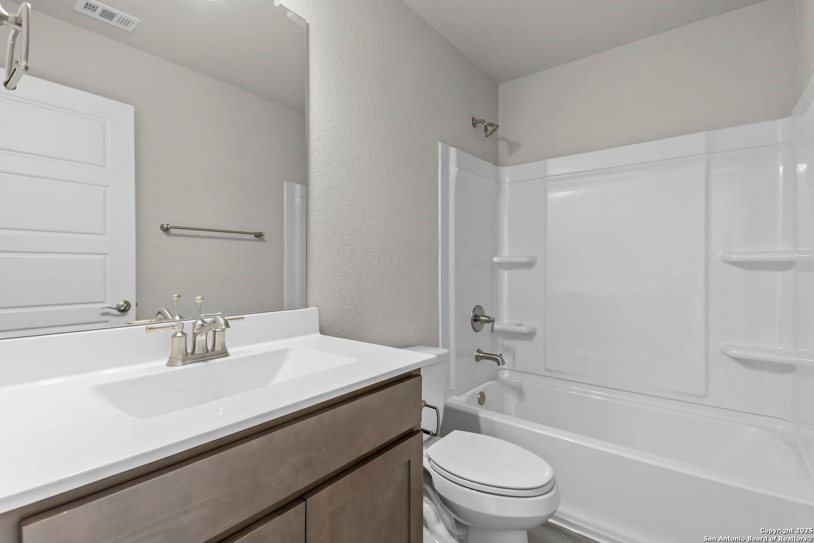 Modern secondary bathroom with white tub-shower combo, single vanity sink, and neutral tones in Davidson Homes The Collin B, Seguin, Texas