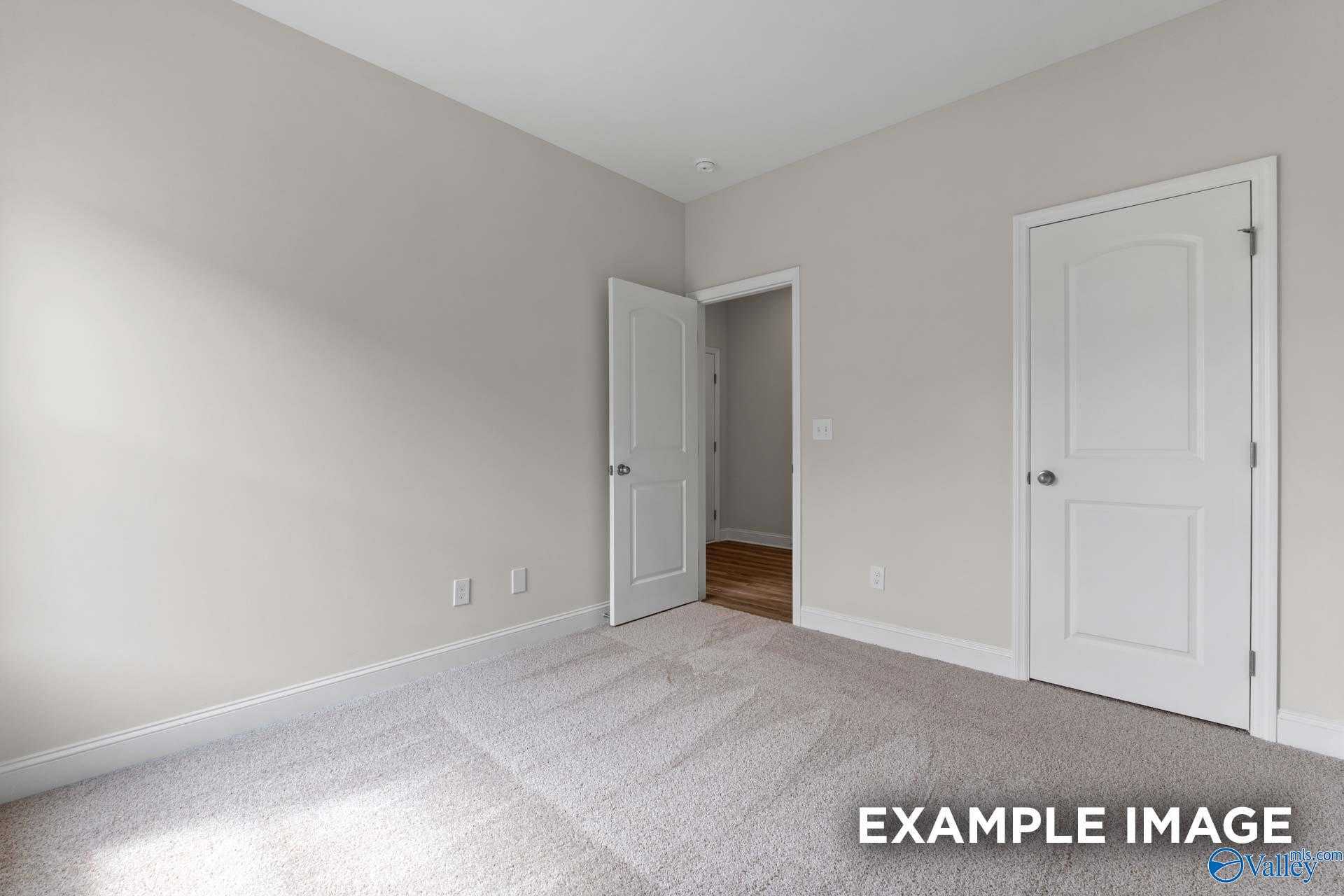 Bright bedroom featuring light gray walls, white doors, and beige carpet in Davidson Homes The Butler, Toney, Alabama