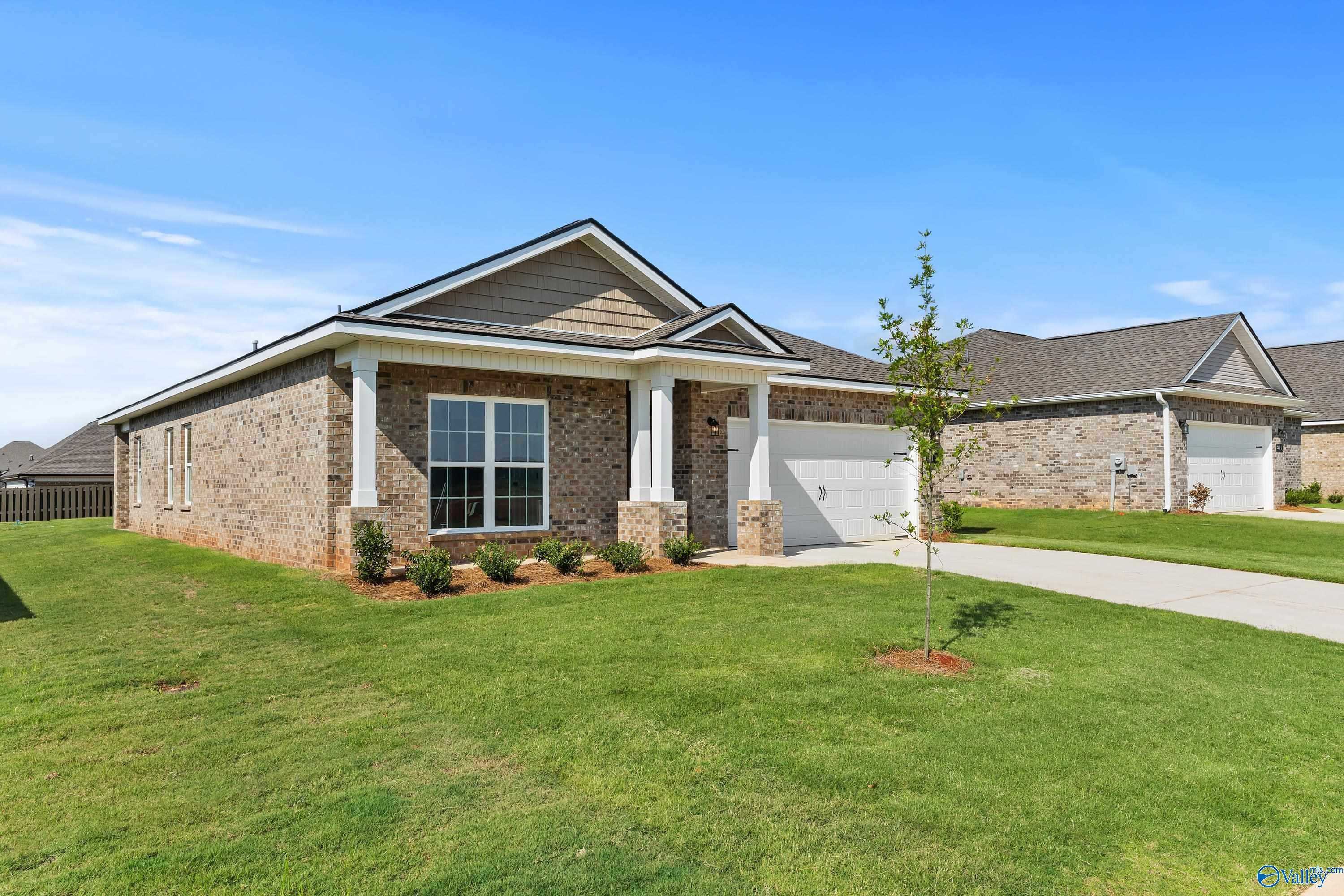 Modern brick ranch home with 2-car garage, covered porch, and lush lawn in Clearview, Hazel Green, Alabama