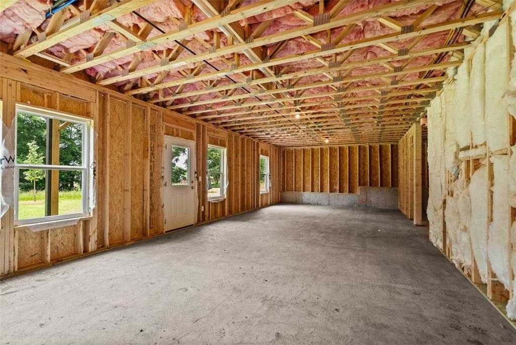 Unfinished basement with wooden framing, pink insulation, concrete floor, and windows in Davidson Homes The Hickory B at Wehunt Meadows, Hoschton