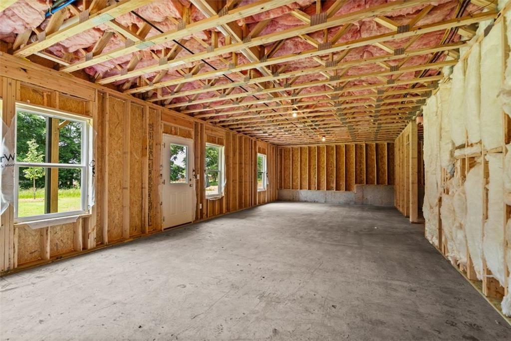 Unfinished basement with wooden framing, pink insulation, concrete floor, and windows in Davidson Homes The Hickory B at Wehunt Meadows, Hoschton
