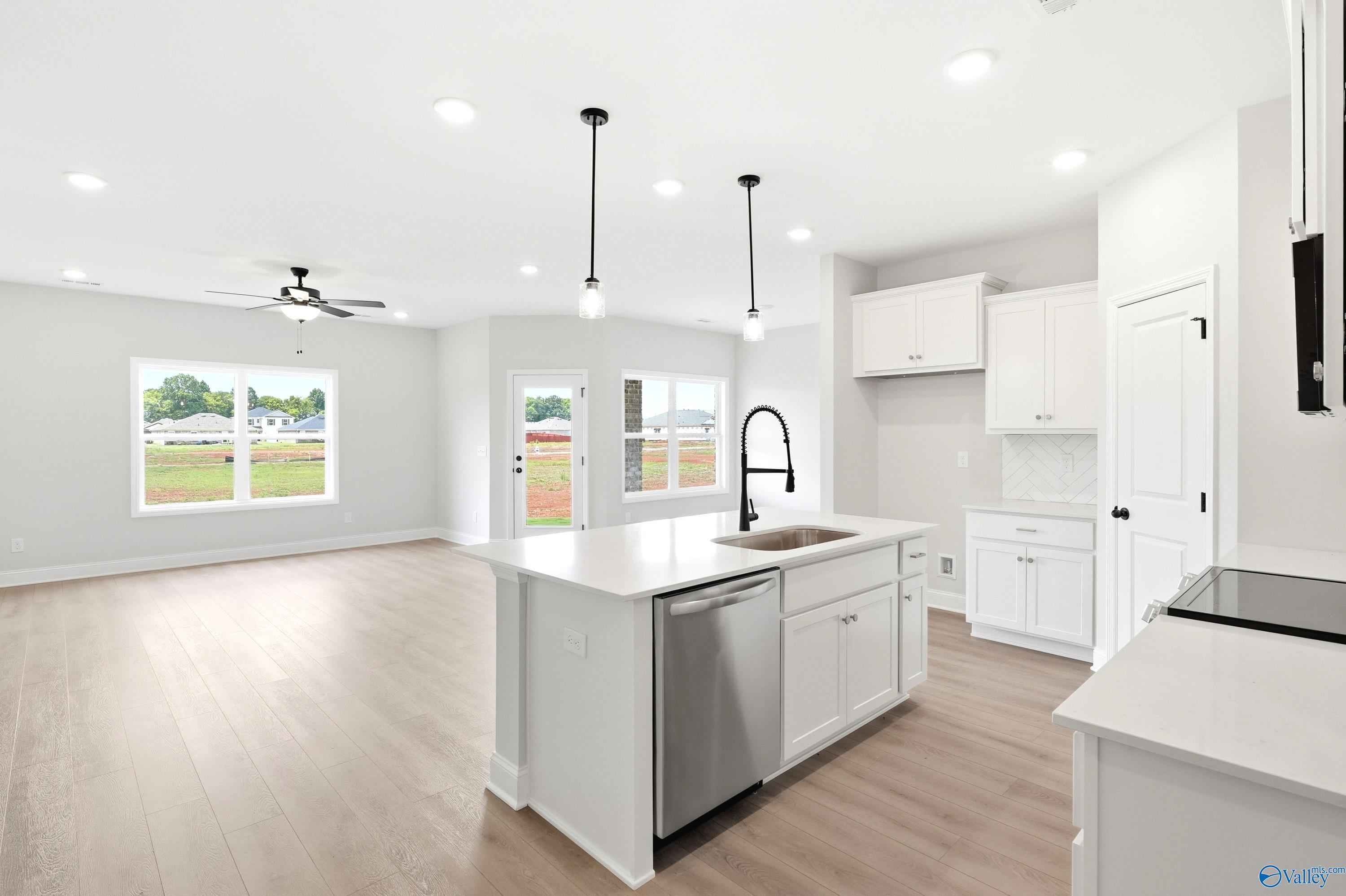 Open-concept kitchen with white cabinets and island in The Daphne floor plan at Lynn Meadows, Meridianville, Alabama.