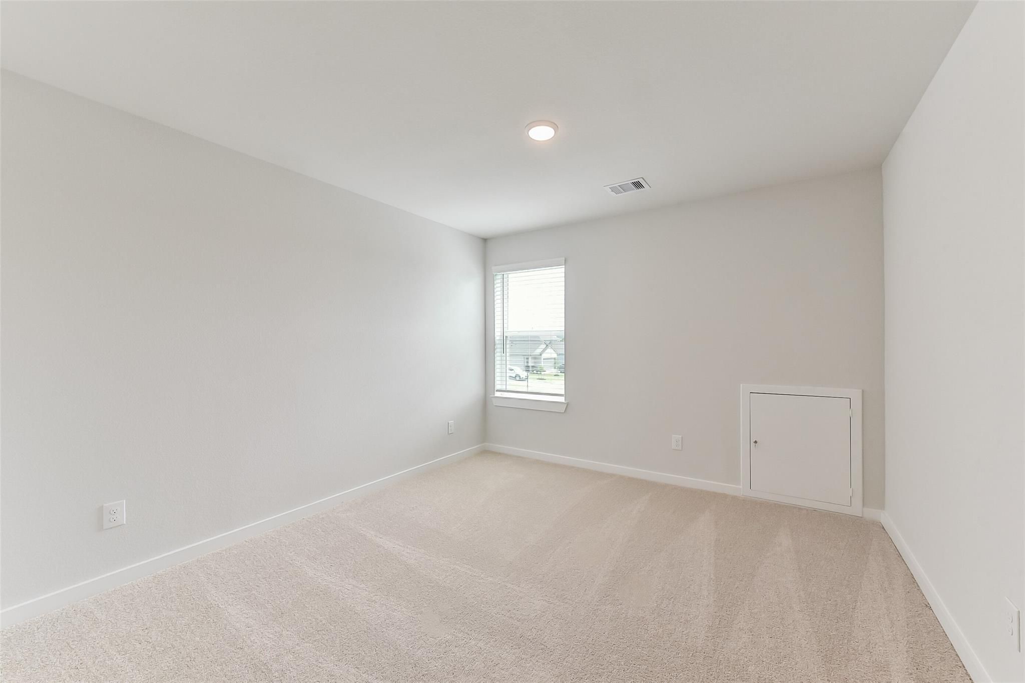 Bright secondary bedroom featuring light gray walls, beige carpet, and window with blinds in 5-bedroom Sabine F home, Dayton, Texas