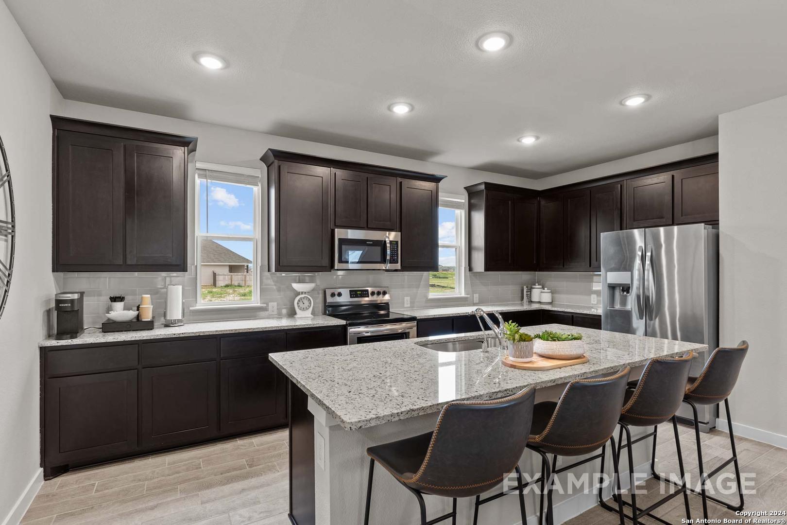 Modern kitchen with dark cabinets, granite island, stainless steel appliances in The Collin A by Davidson Homes, Seguin, Texas