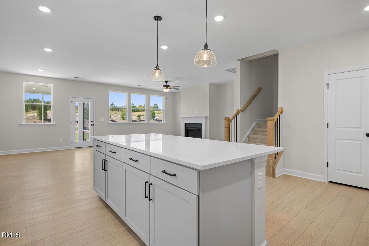 Open-concept kitchen with white island, hardwood floors, and fireplace in Davidson Homes Ashport M plan, Wendell Ridge, NC