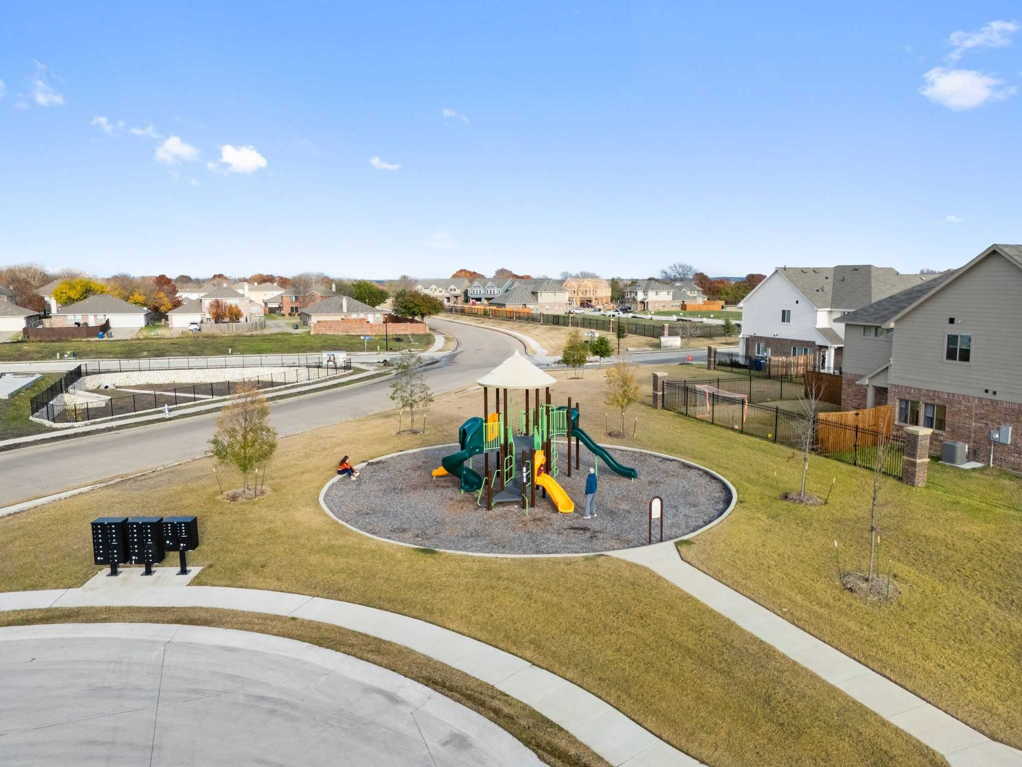 Vibrant playground with slides, swings and kids in community park surrounded by modern homes in Lake Park Villas, Wylie, Texas