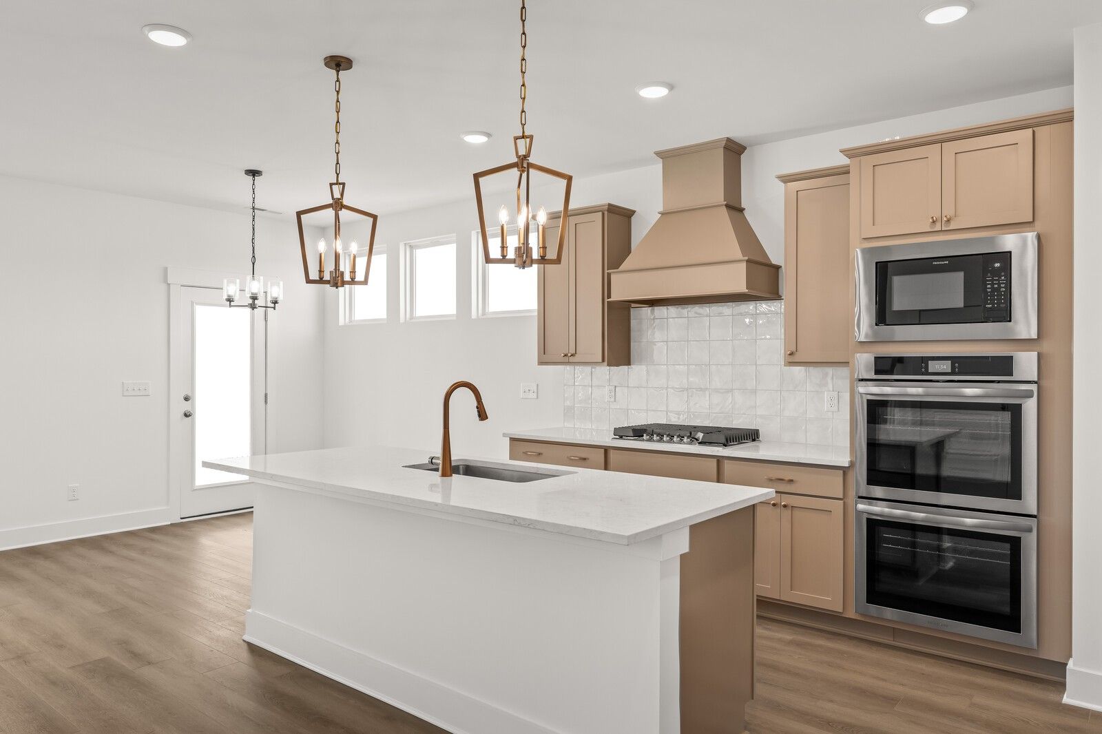 Bright open-concept kitchen with white shaker cabinets, stainless double ovens, and large island in Davidson Homes The Ash A, Gallatin, TN