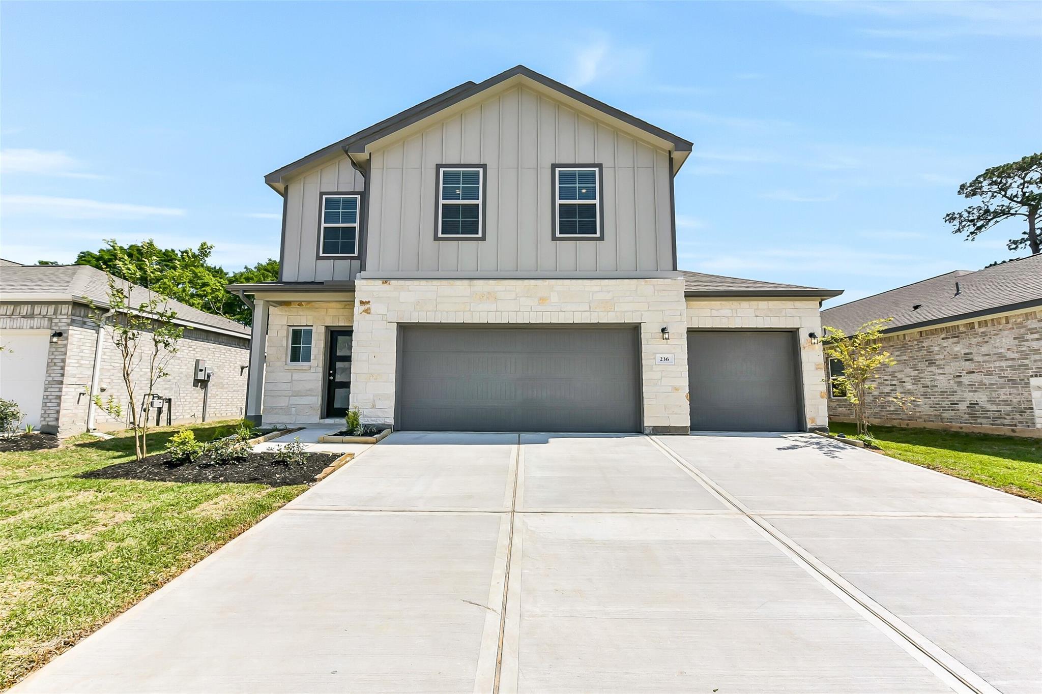Modern two-story 5-bedroom home with stone facade, 3-car garage, and landscaped driveway in Windmill Estates, Magnolia, Texas