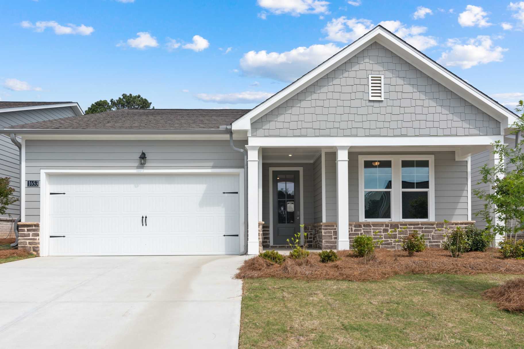 Front elevation of Dawson A single-story home in Loganville GA featuring gray siding, 2-car garage, covered porch, and landscaped yard