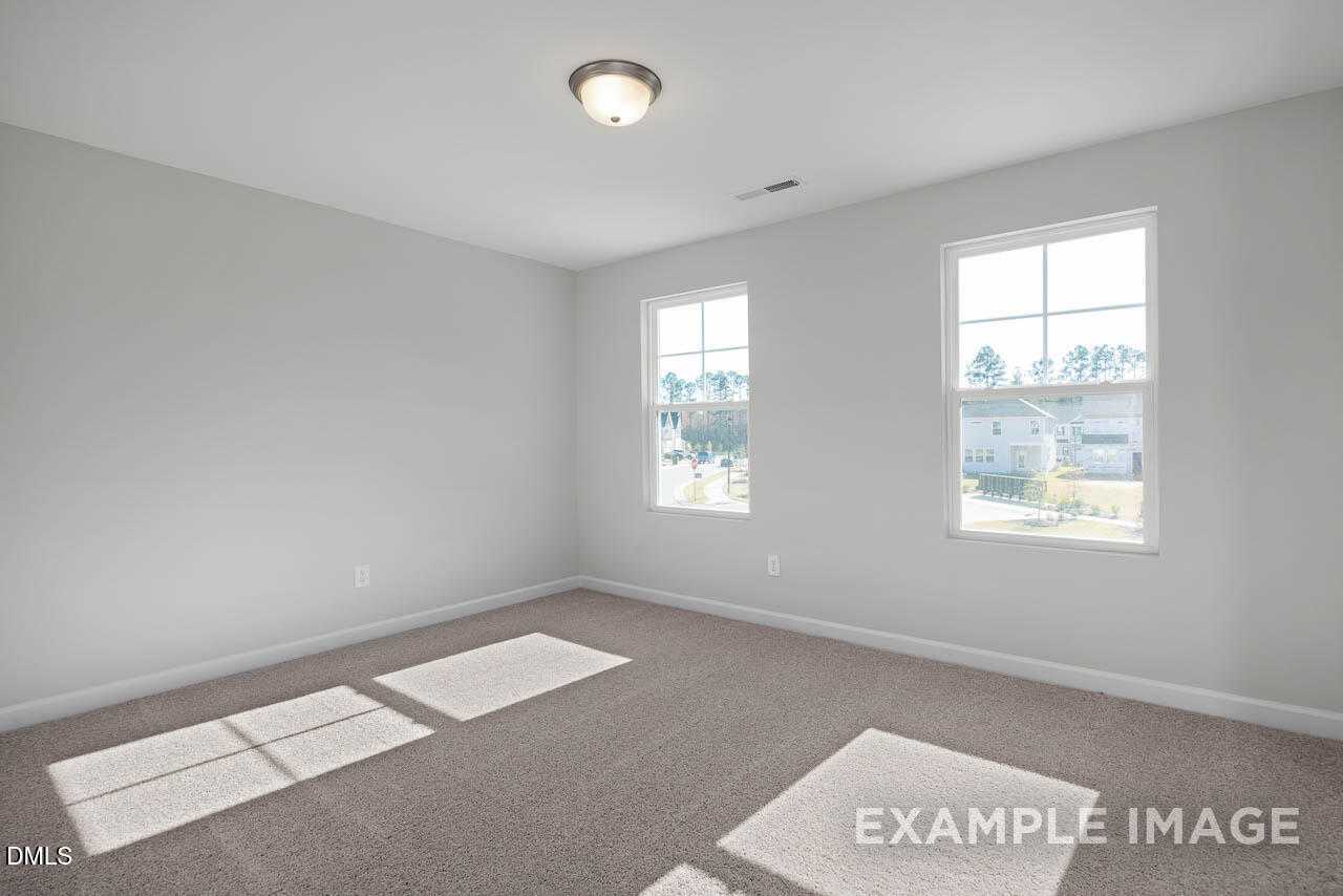 Bright secondary bedroom with gray walls, beige carpet, large windows in Davidson Homes The Adalynn A, Lillington, NC