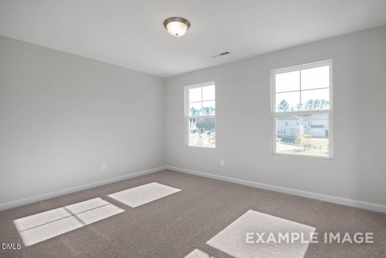 Bright secondary bedroom with gray walls, beige carpet and large windows in The Adalynn A 4-bedroom home, Lillington, NC
