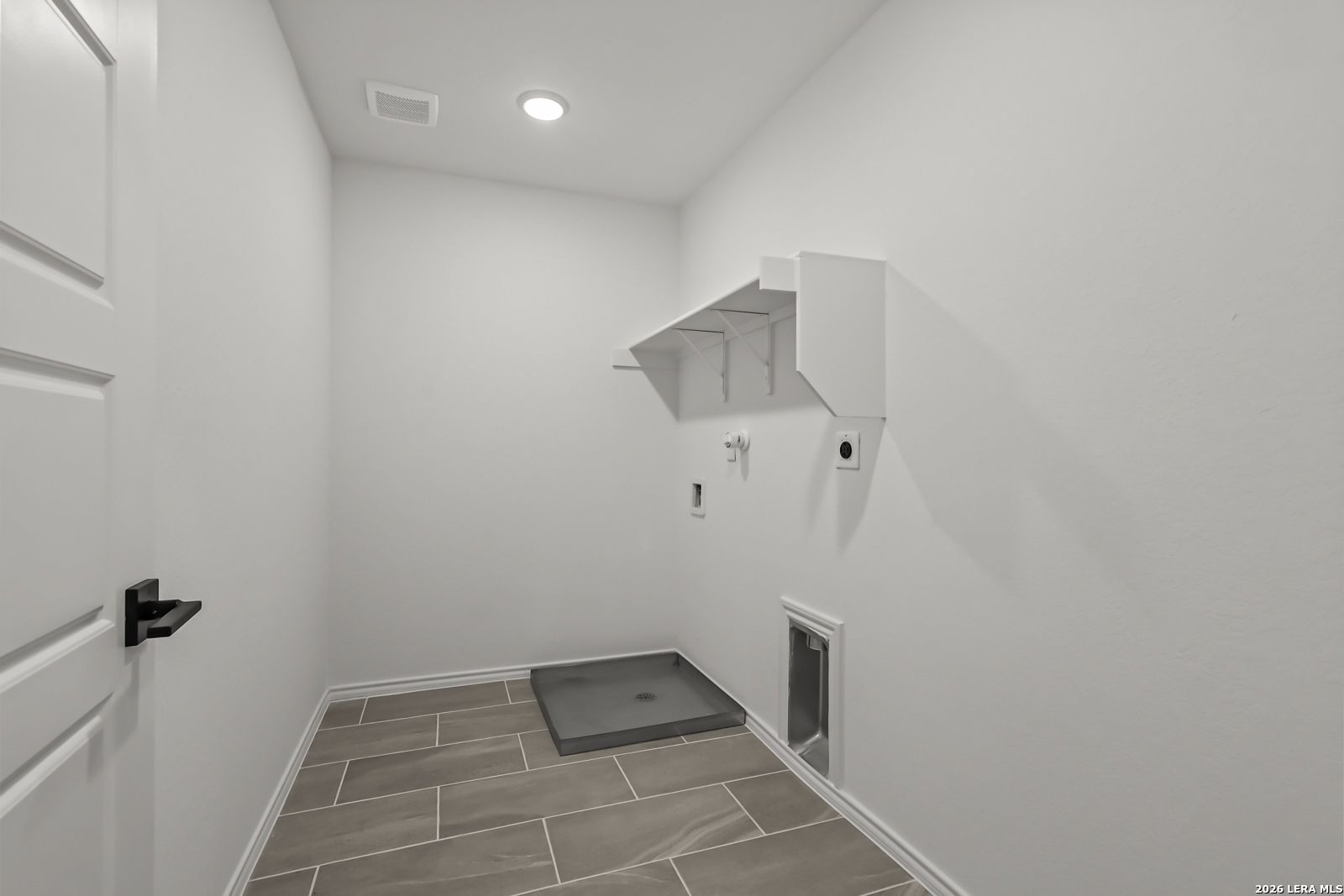 Laundry room with tile flooring and storage shelving in The Florence B floor plan at Meadows at Oak Creek, San Antonio.