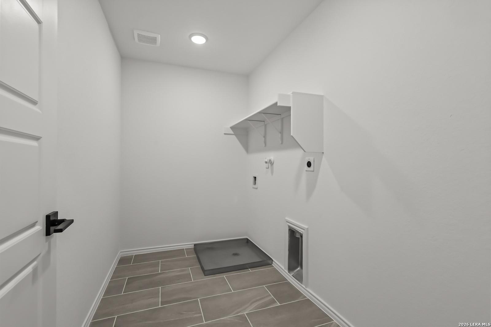 Laundry room with tile flooring and storage shelving in The Florence B floor plan at Meadows at Oak Creek, San Antonio.