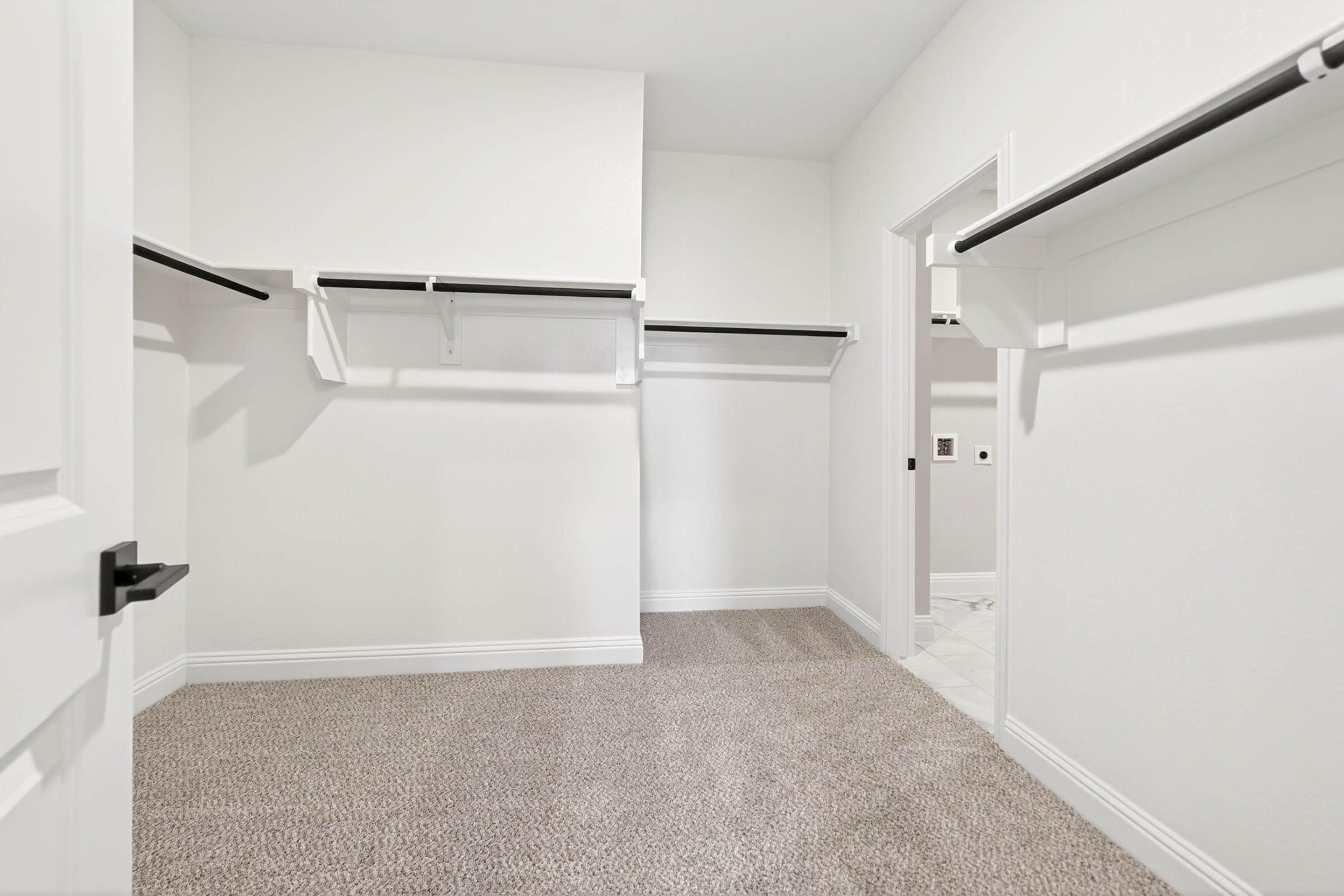 Spacious walk-in closet in The Holly master suite with built-in shelving and carpeted floors.