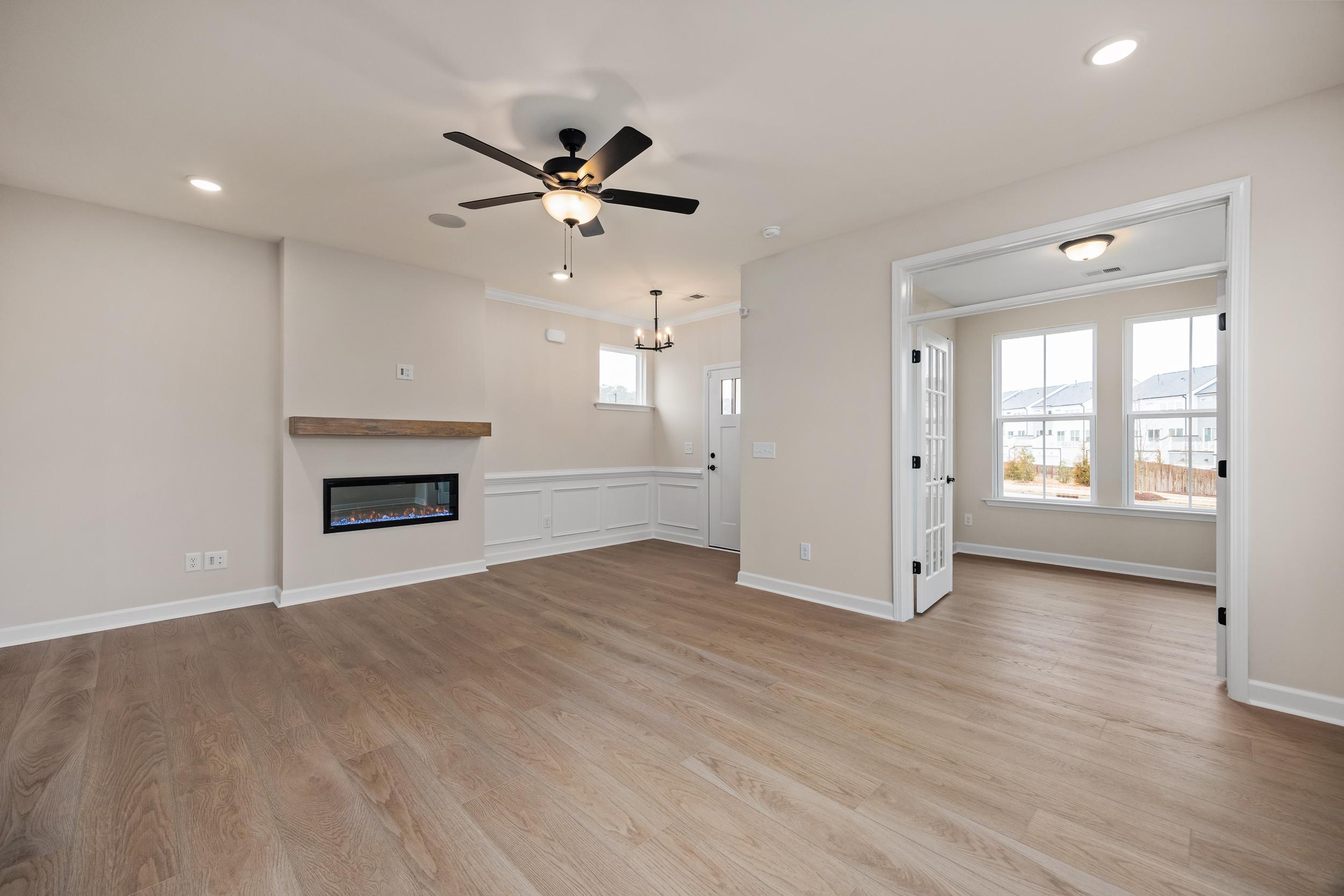 Spacious open-concept living room at Forestville Yard in Knightdale NC with hardwood floors, gas fireplace, and large windows