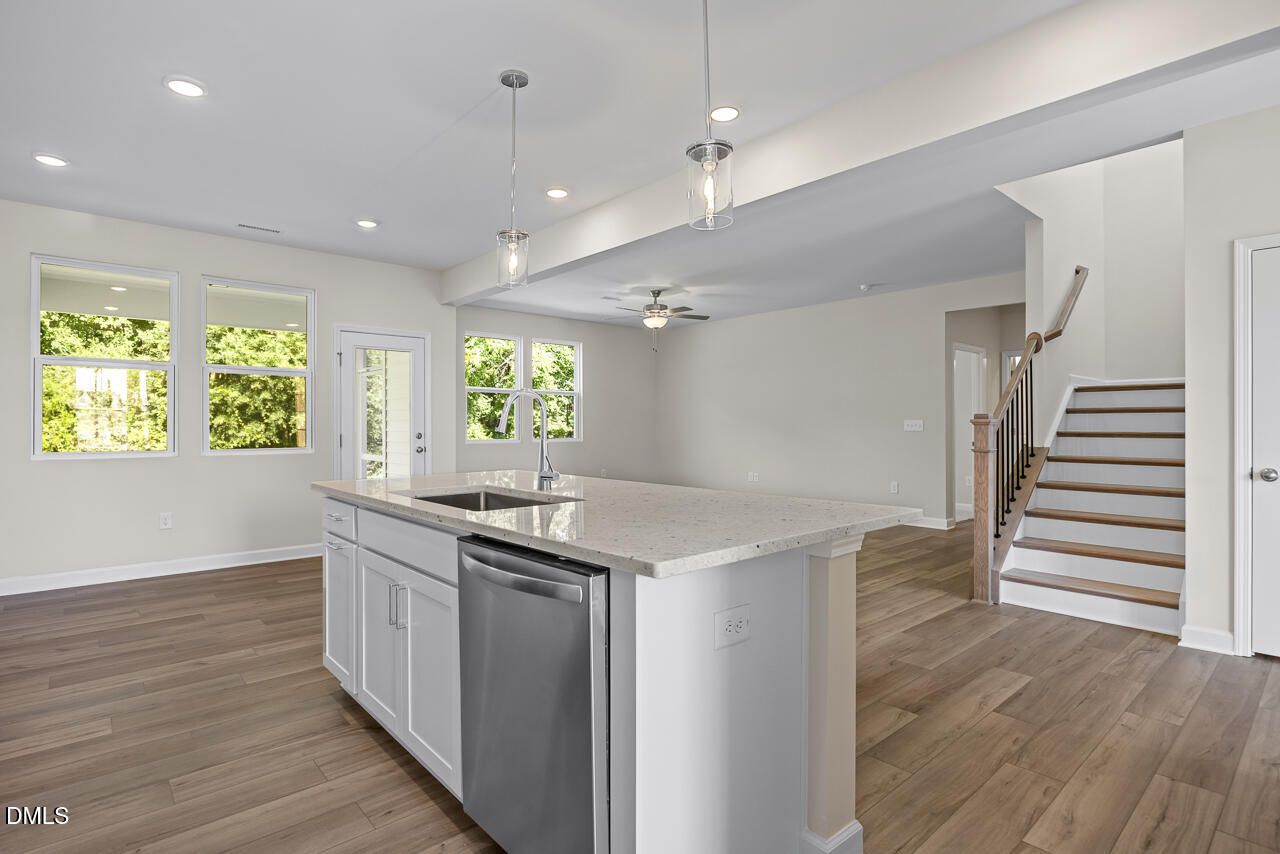 Open-concept kitchen with white island, quartz countertops, and hardwood floors in Davidson Homes Willow C plan, Zebulon NC