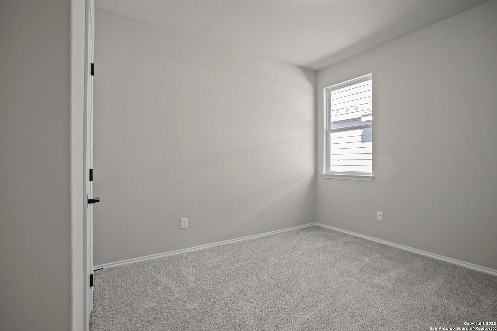 Bright secondary bedroom featuring gray walls, plush carpet, and sunlit window in The Asheville H by Davidson Homes, Converse, TX