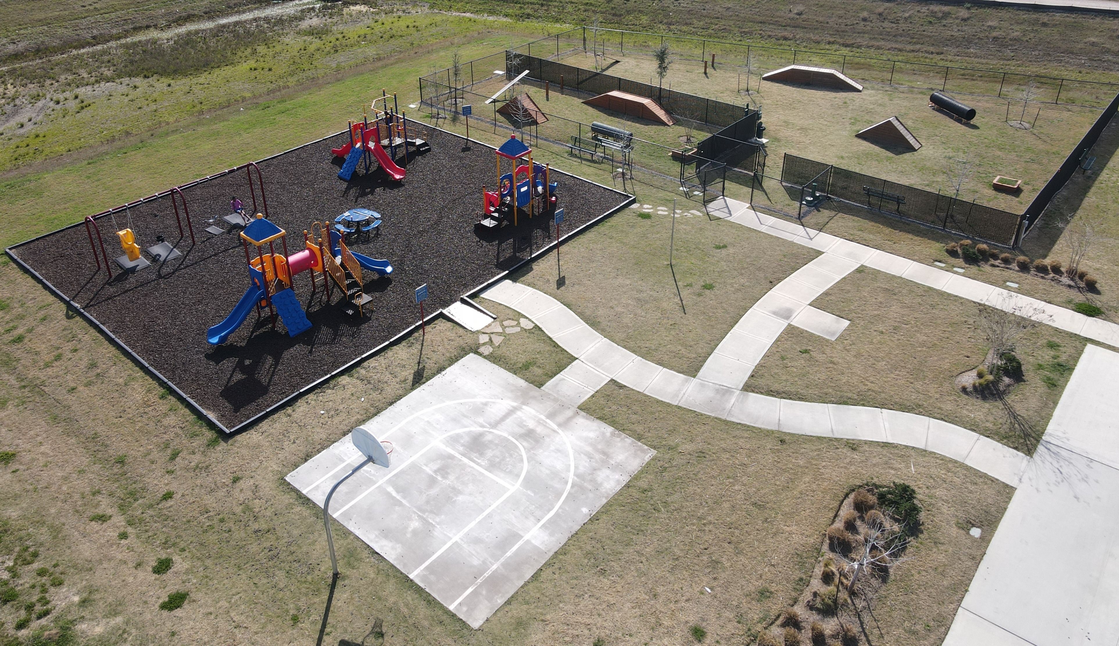 Vibrant playground with colorful slides, climbers and basketball court at The Villages at WestPointe in Dayton Texas by Davidson Homes