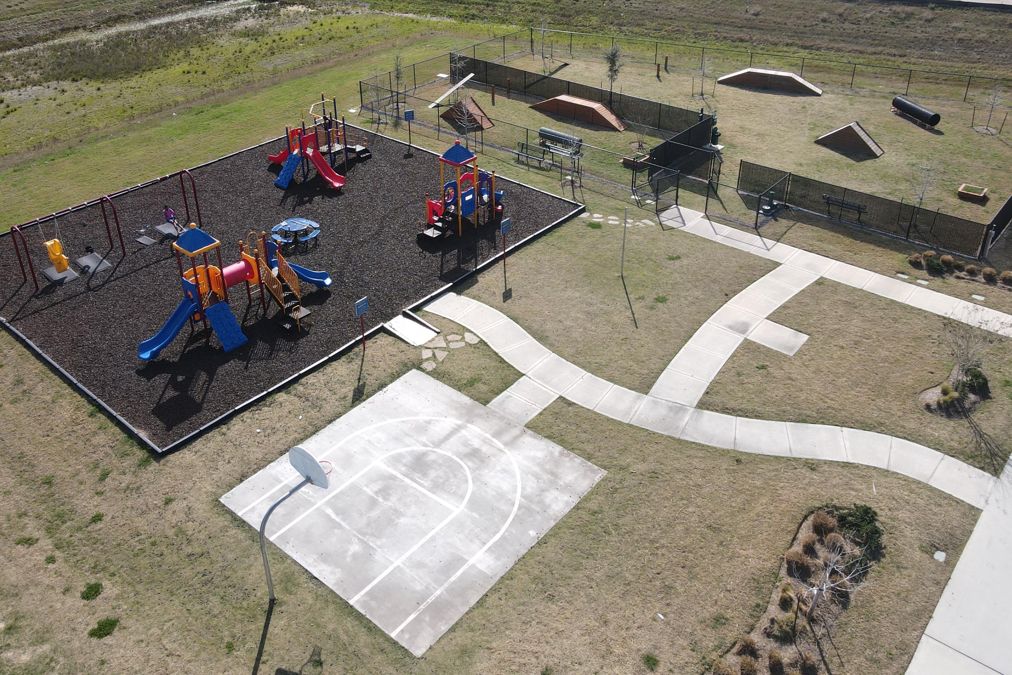 Vibrant playground with colorful slides, climbers and basketball court at The Villages at WestPointe in Dayton Texas by Davidson Homes