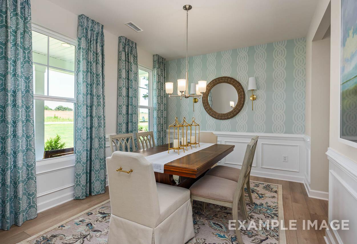 Formal dining room in The Willow C-BF by Davidson Homes featuring wainscoting, patterned wallpaper, and chandelier.