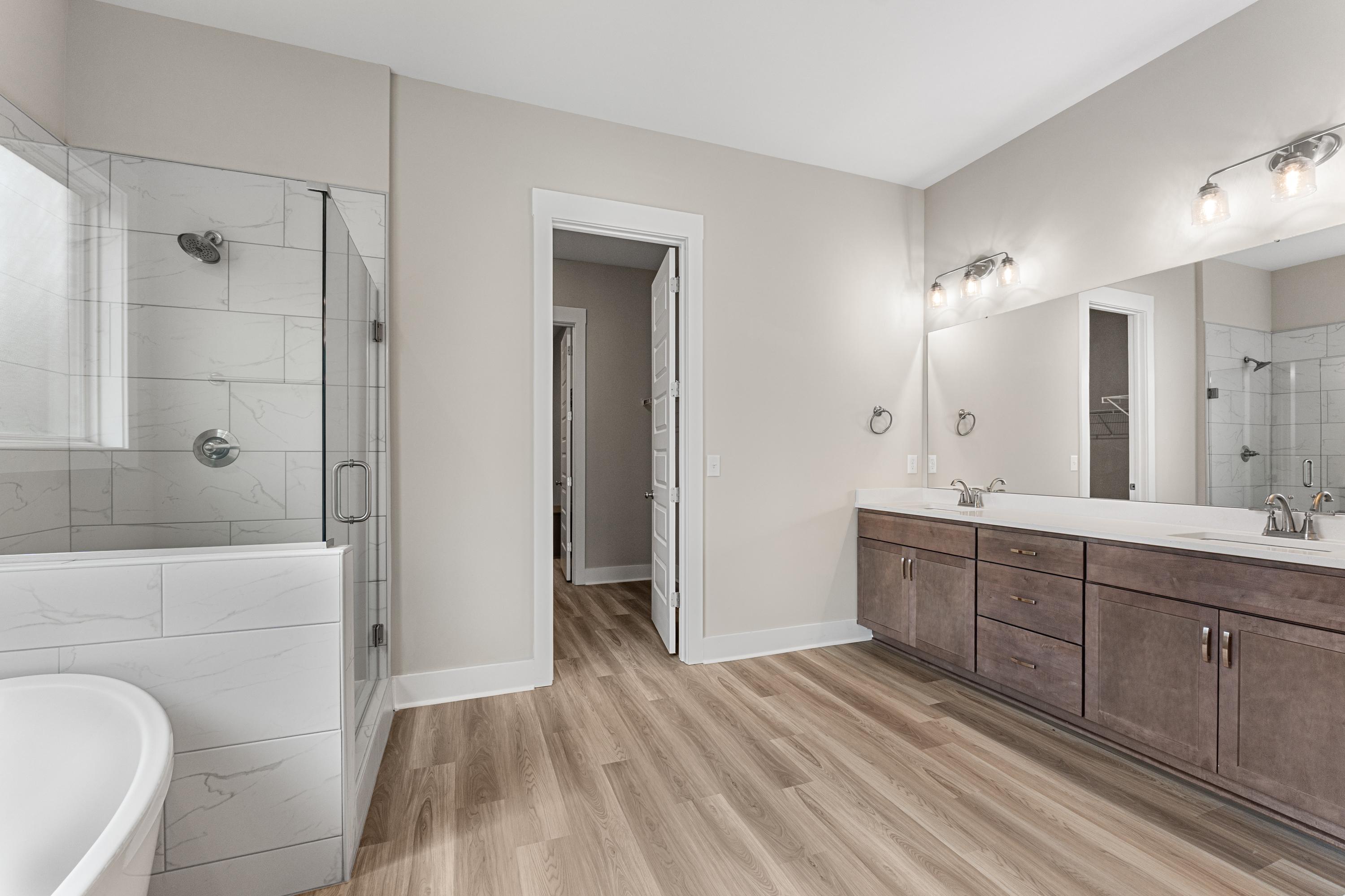 Spacious master bathroom in The Oxford C featuring frameless glass shower, double vanity sinks, and neutral tones