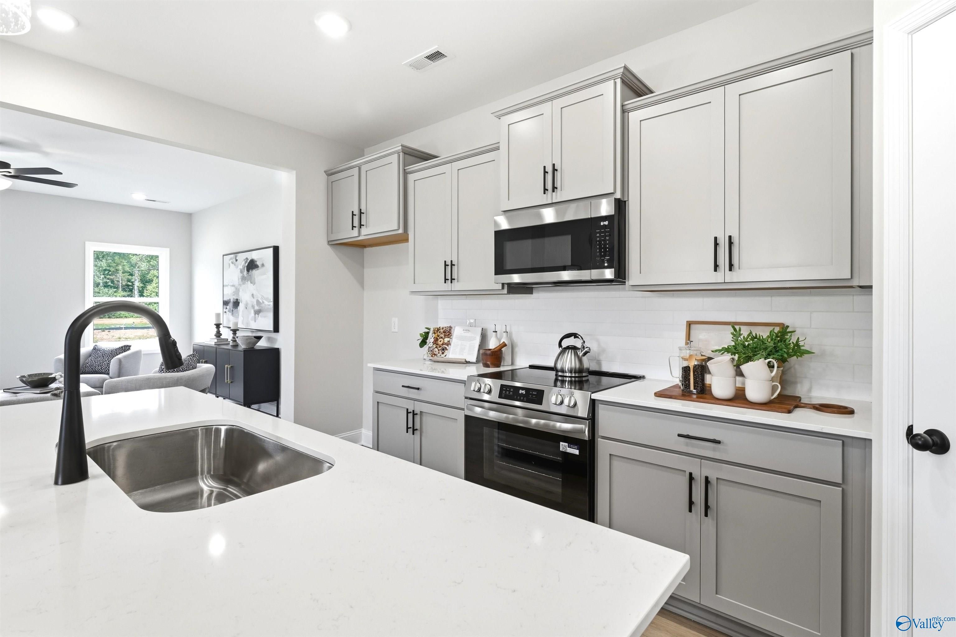 Modern kitchen with gray shaker cabinets, stainless appliances, and white island sink in Davidson Homes The Russell A, Huntsville