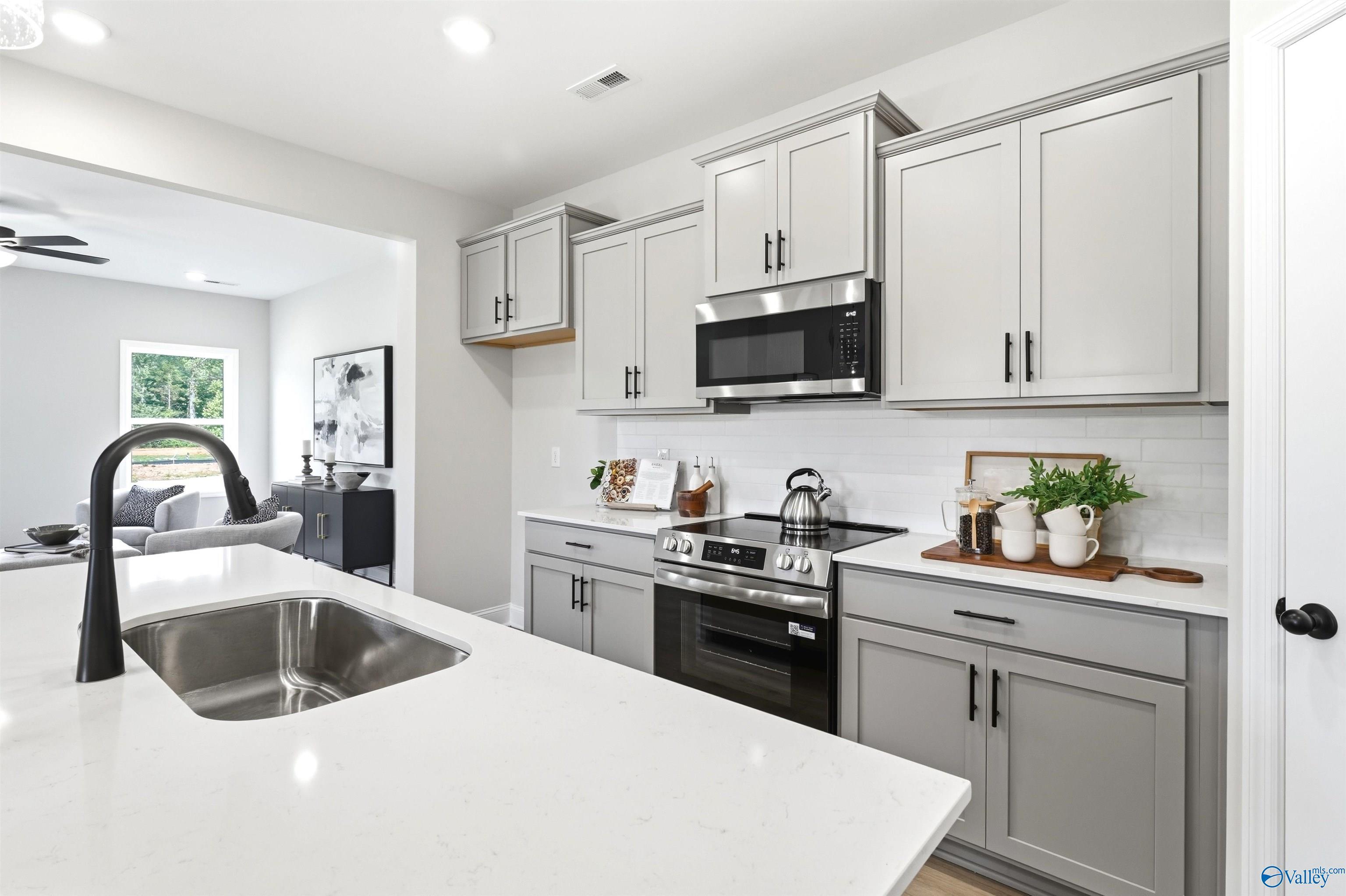 Modern kitchen with gray shaker cabinets, stainless appliances, and white island sink in Davidson Homes The Russell A, Huntsville