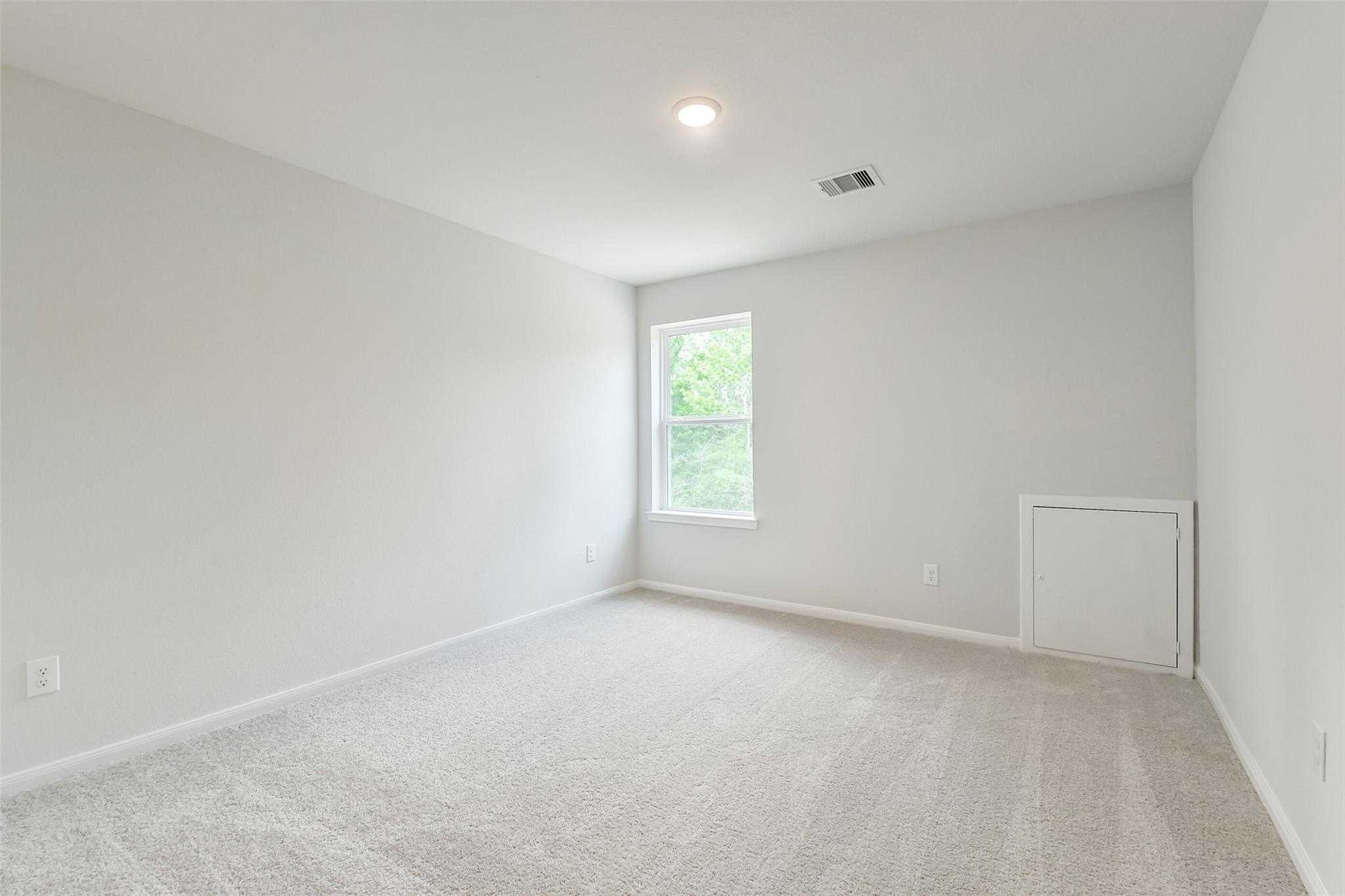 Bright secondary bedroom with neutral gray walls, plush carpet, and sunny window in Davidson Homes The Sabine E, Conroe TX