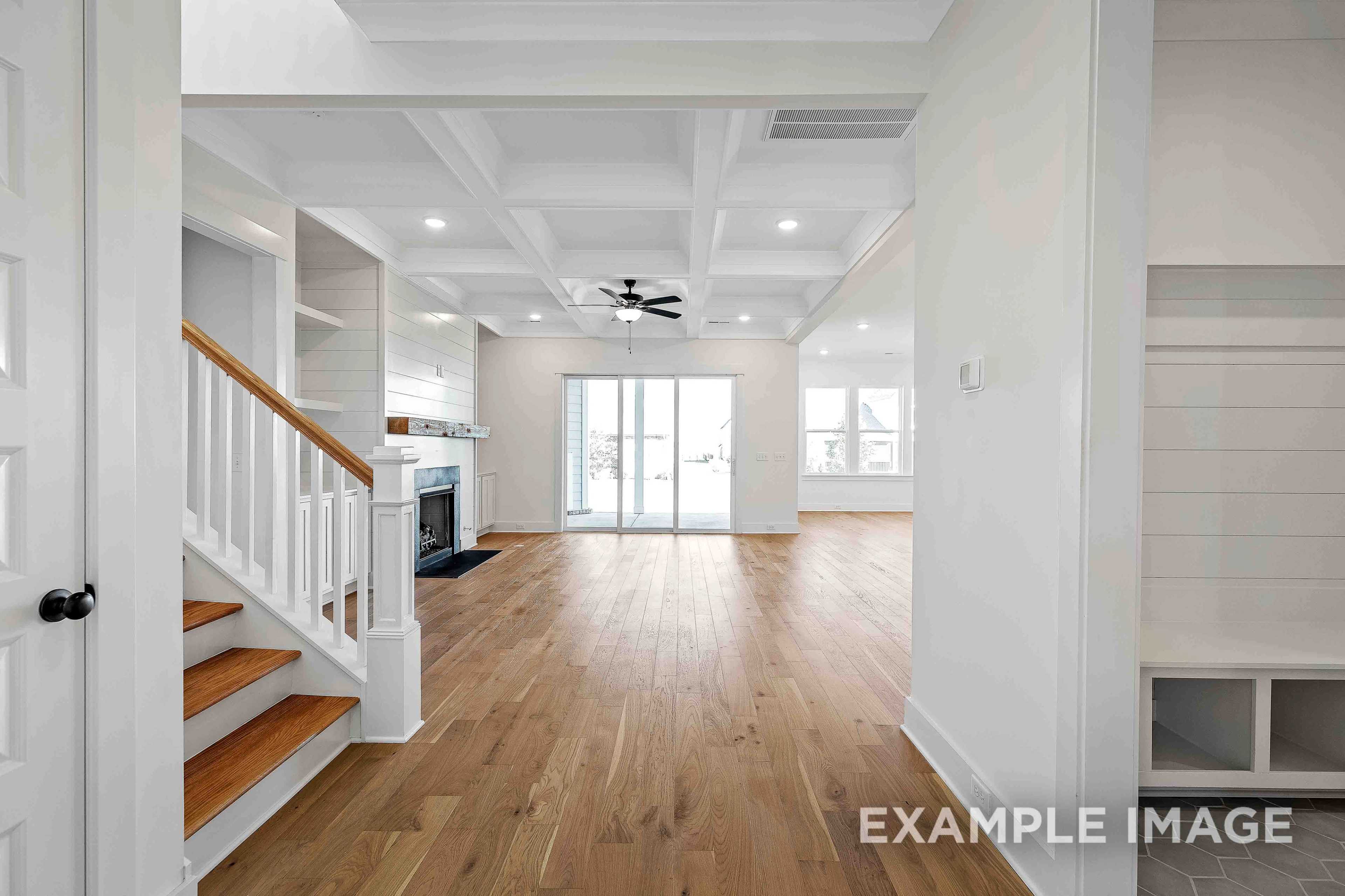 Spacious entryway in The Albany A 2-story home with curved oak staircase, coffered ceiling fan, and open hardwood floor plan